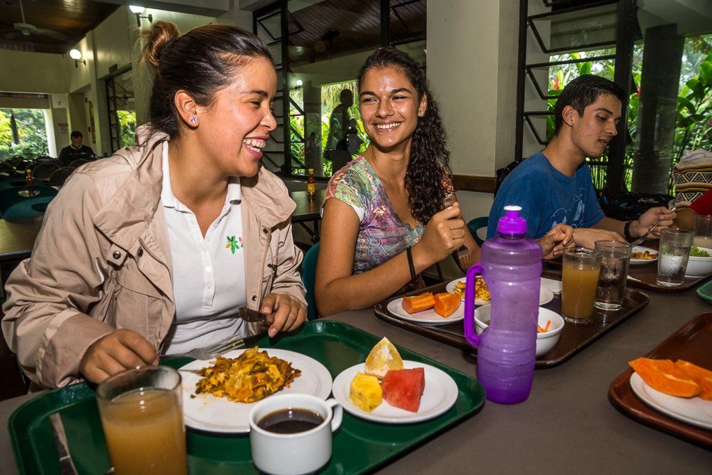 A group of people are sitting at a table eating food from a tray.