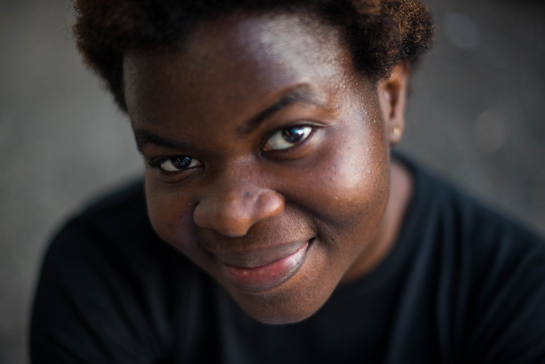 A woman in a black shirt is smiling and looking at the camera.