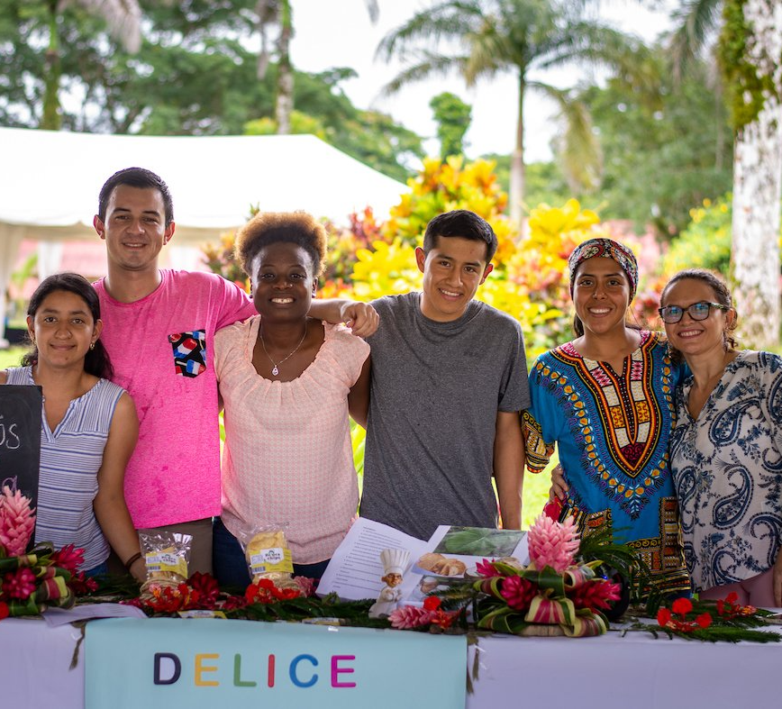 A group of people posing for a picture in front of a sign that says delice