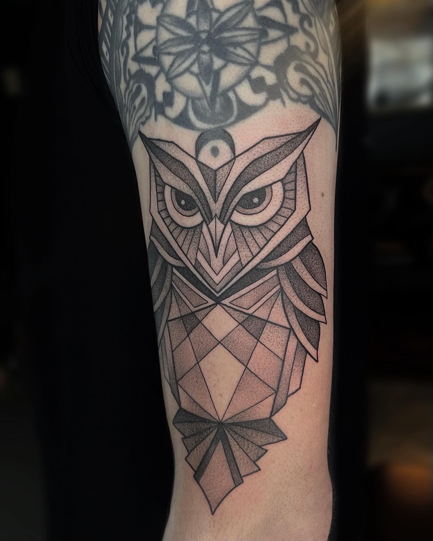 Geometric owl tattoo on arm with intricate linework.