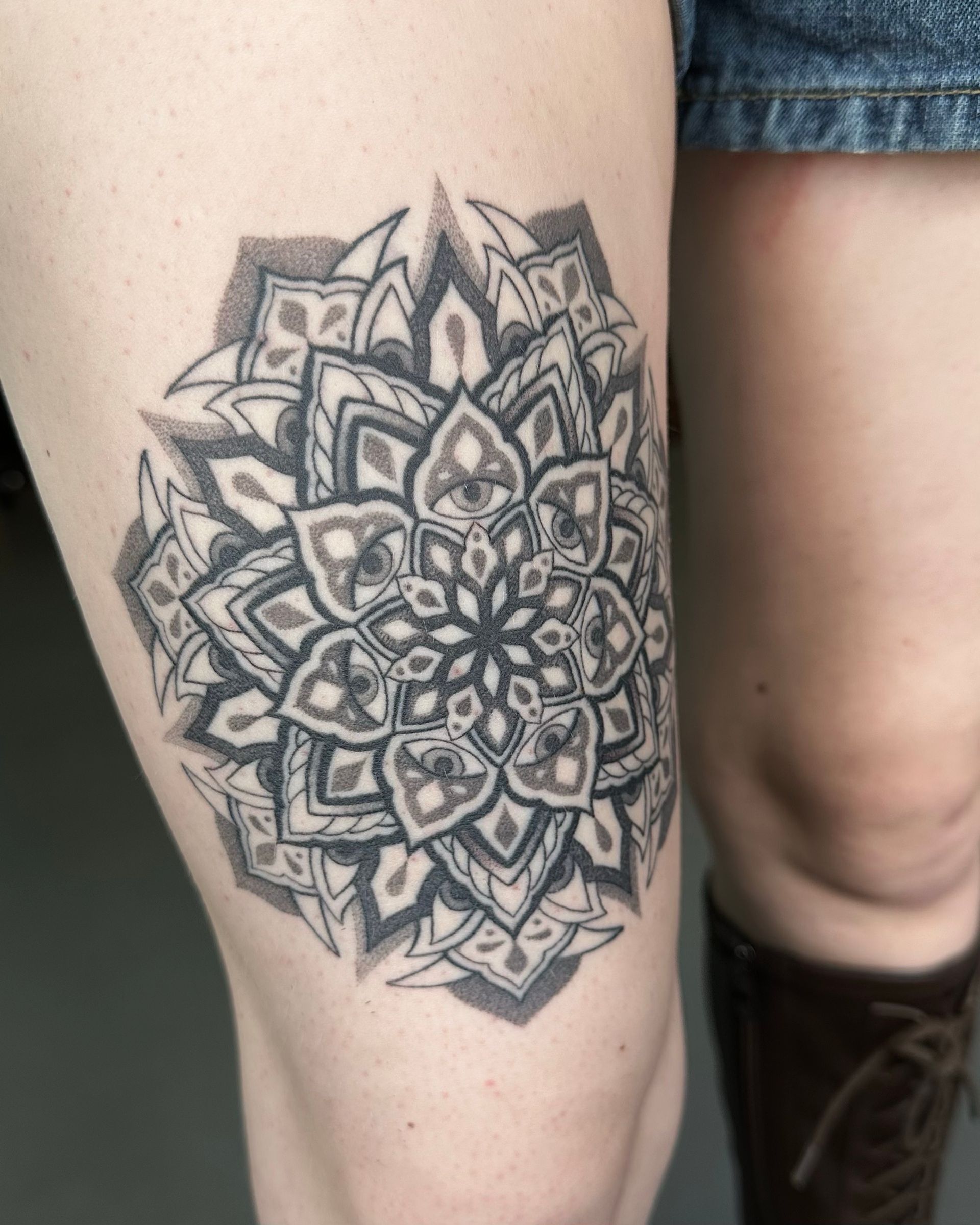 Black and gray mandala tattoo on a leg.