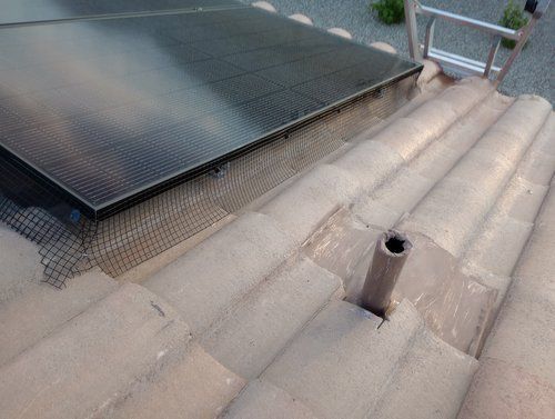 A solar panel is sitting on top of a tiled roof.