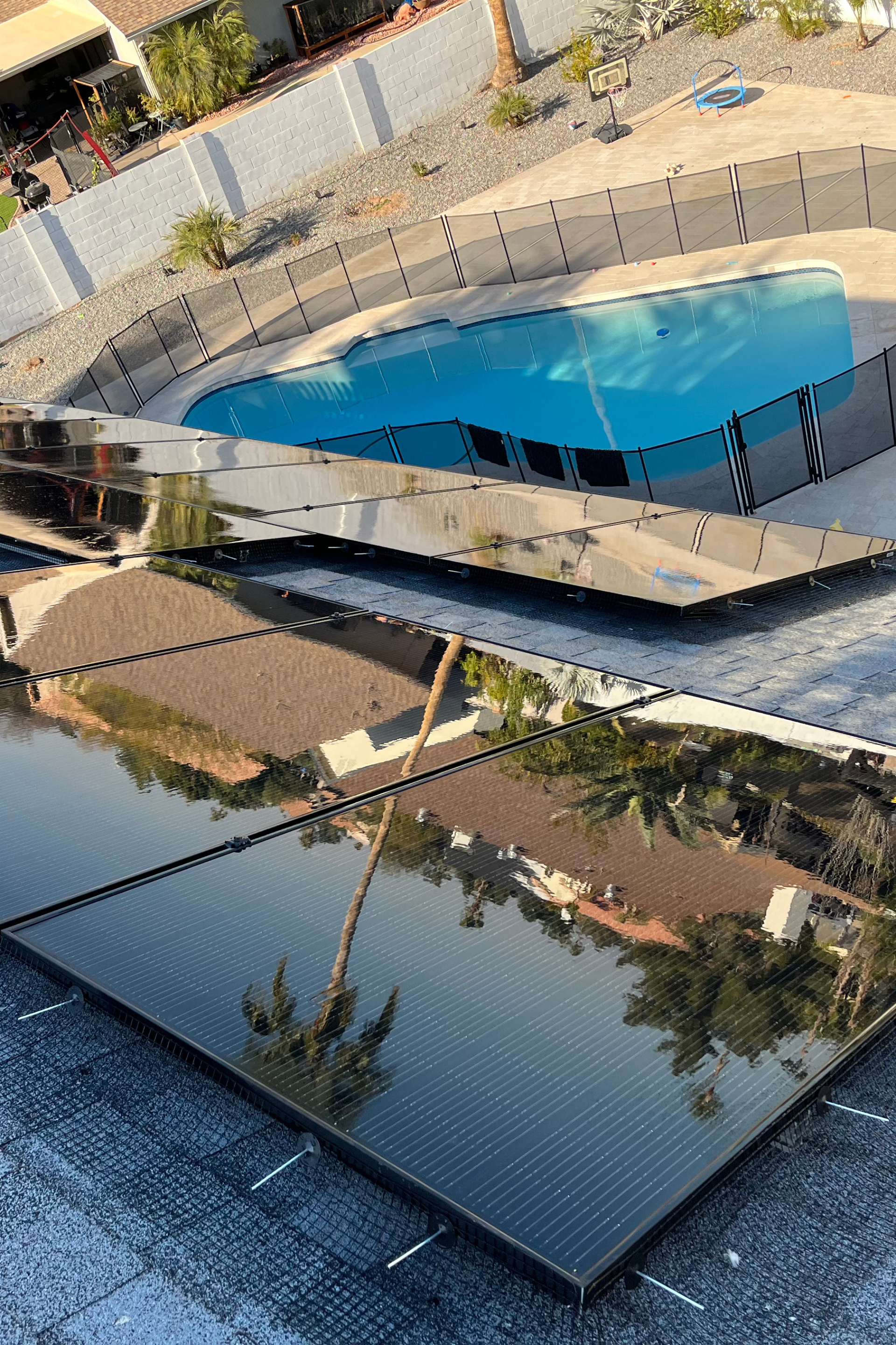 A swimming pool is reflected in the solar panels on the roof.