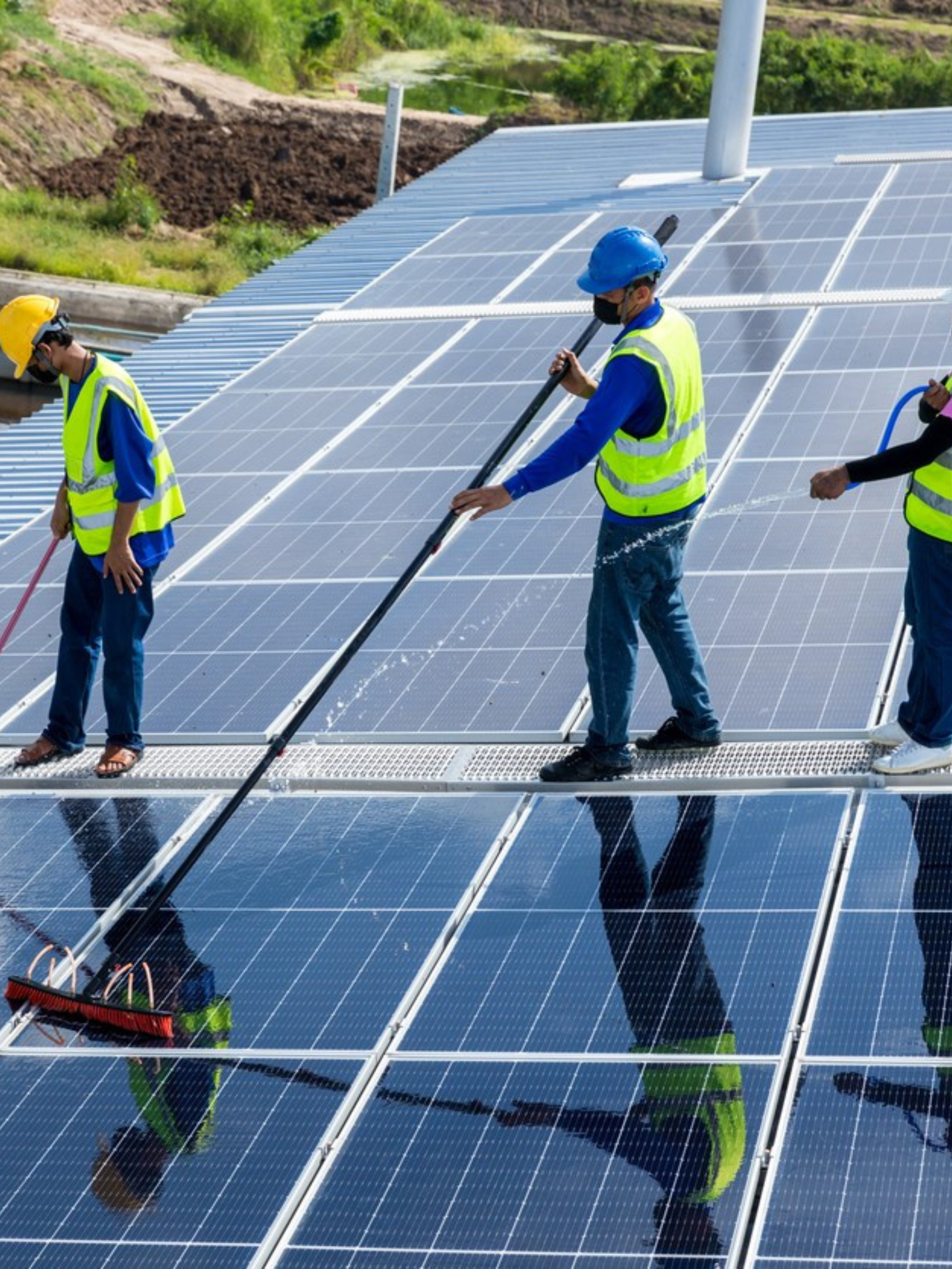 A group of people are cleaning solar panels with a broom.