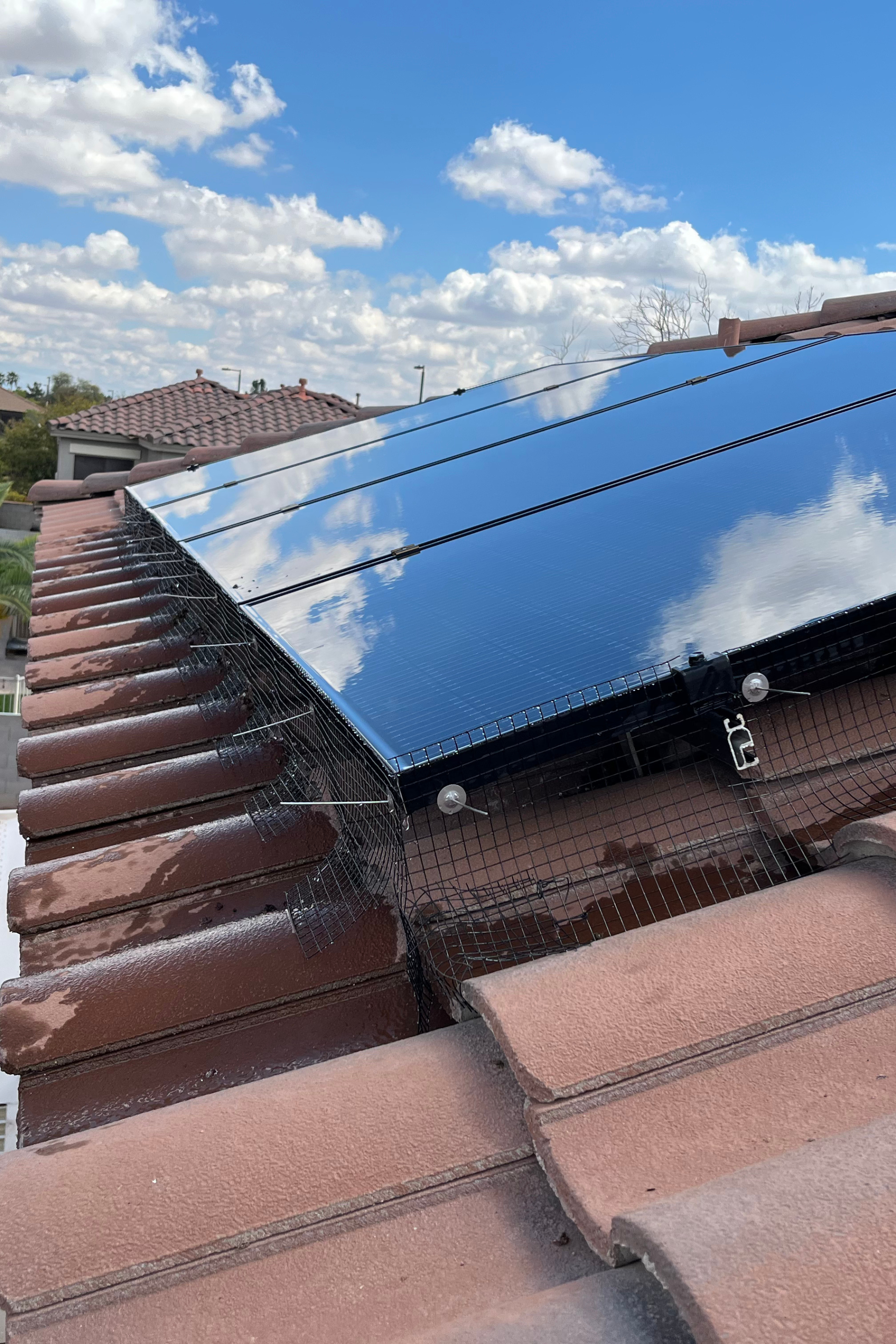 A solar panel is sitting on top of a tiled roof.