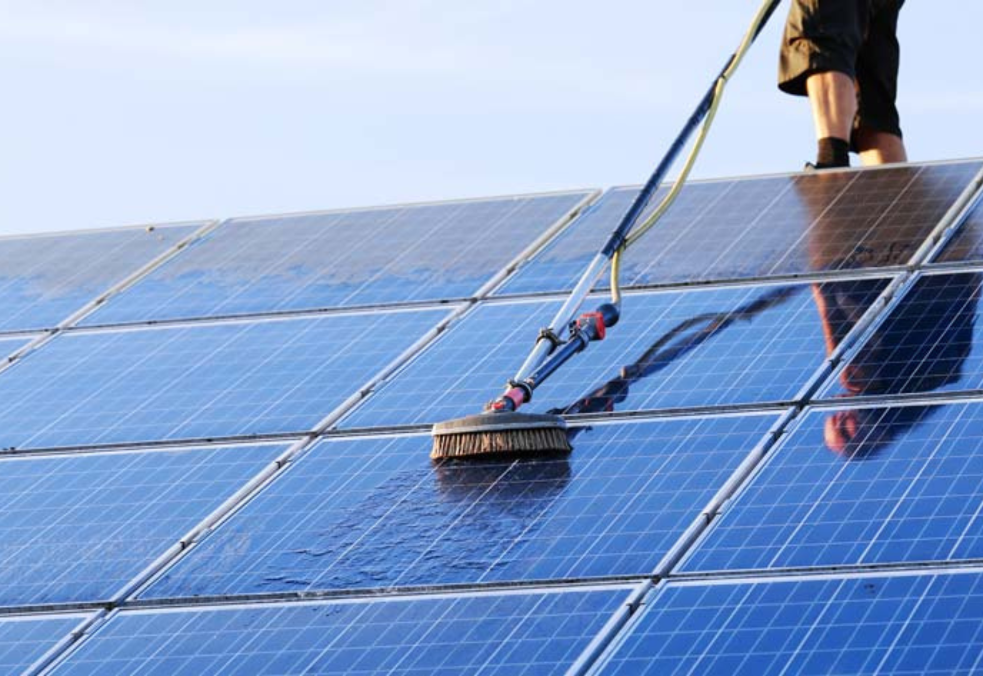 A person is cleaning solar panels with a brush