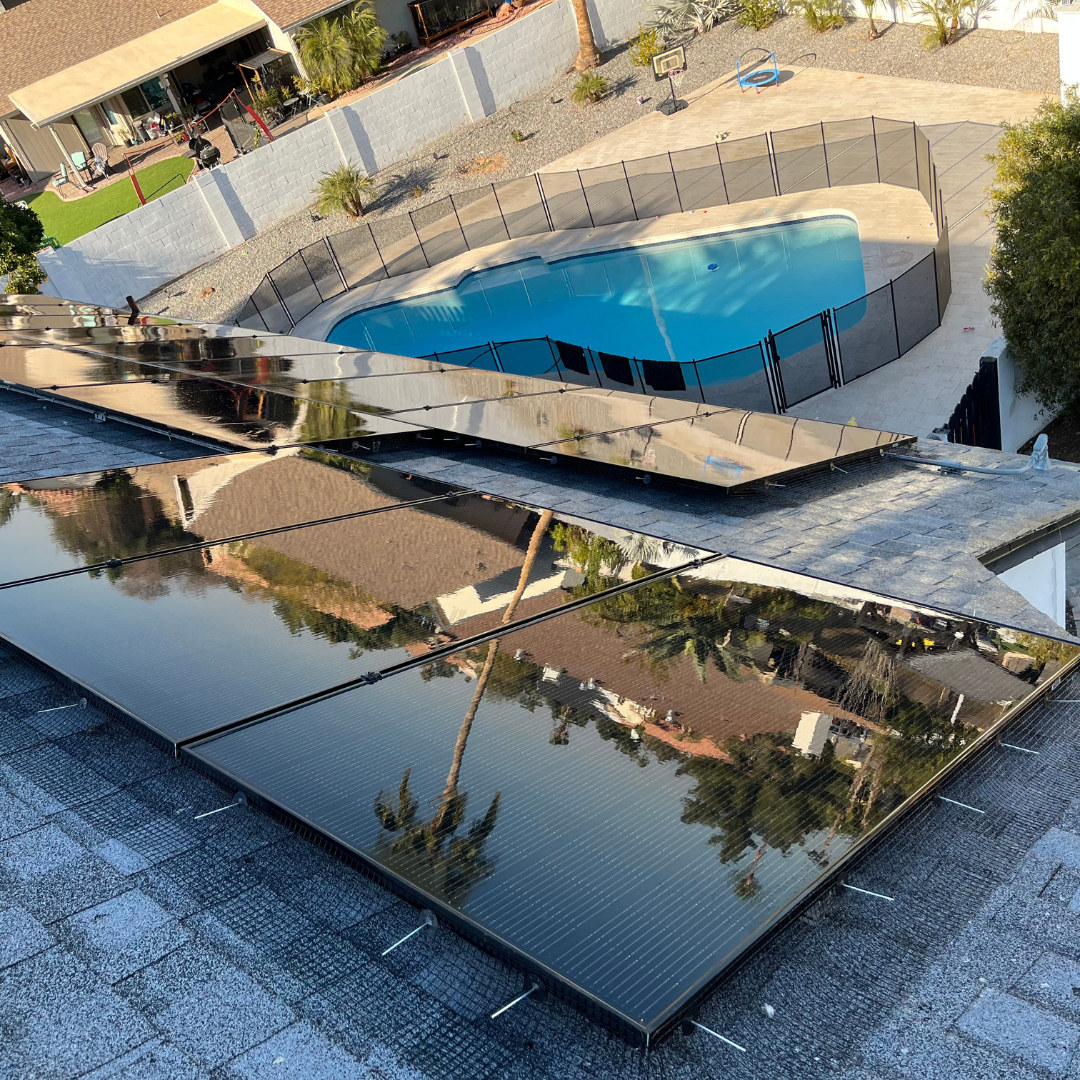 A large solar panel is sitting on top of a roof next to a pool.