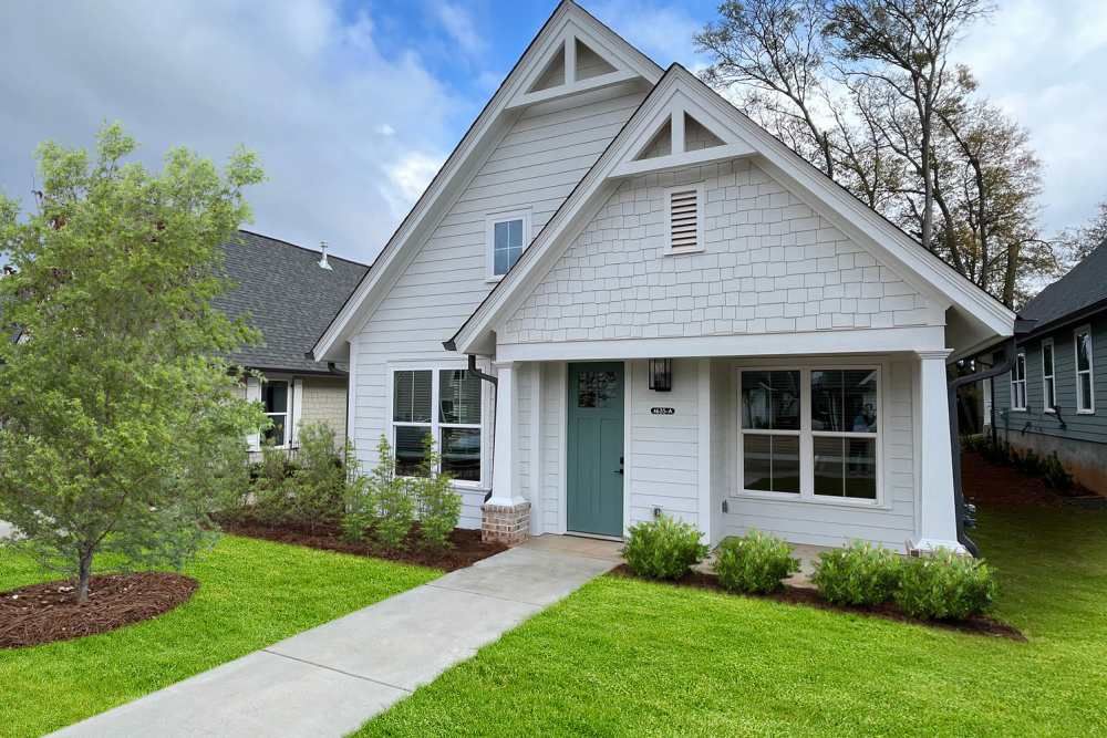 White house with blue door, white trim, and green lawn.