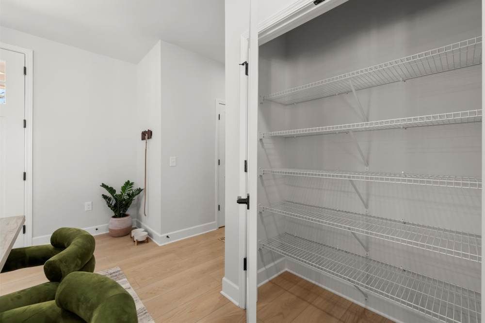 Empty pantry with wire shelves at Hayloft Big Creek, offer 55+ apartments for rent in Alpharetta, GA. Light wood floor and white walls.