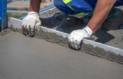 A man is laying concrete on the ground.