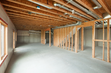 An empty basement under construction with wooden beams and a staircase.