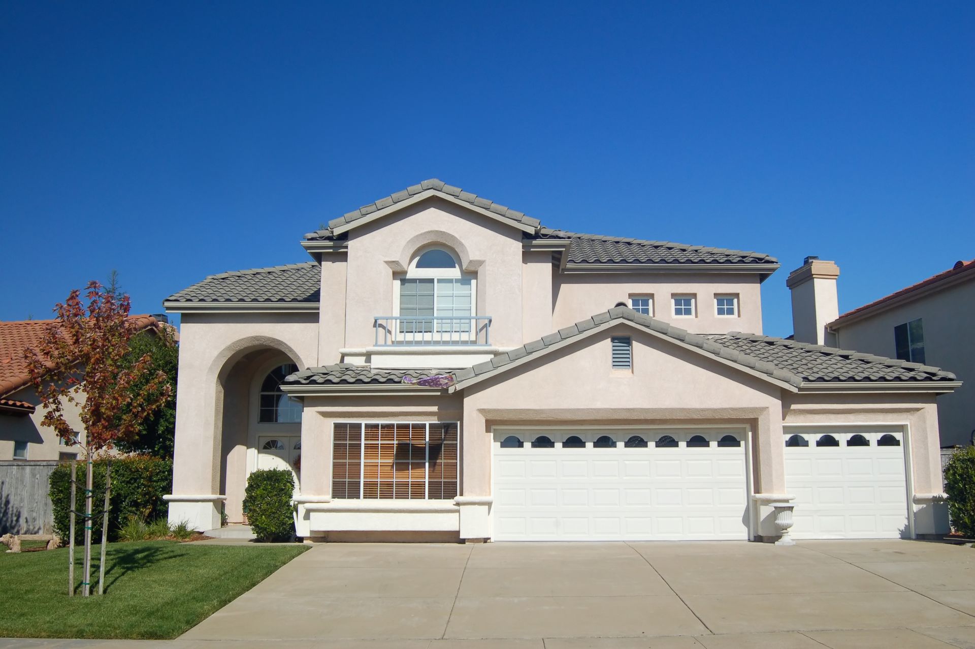 White-tiled bathroom with wooden shelves holding towels, plants, and toiletries. Gray patterned towel hanging on the left.
