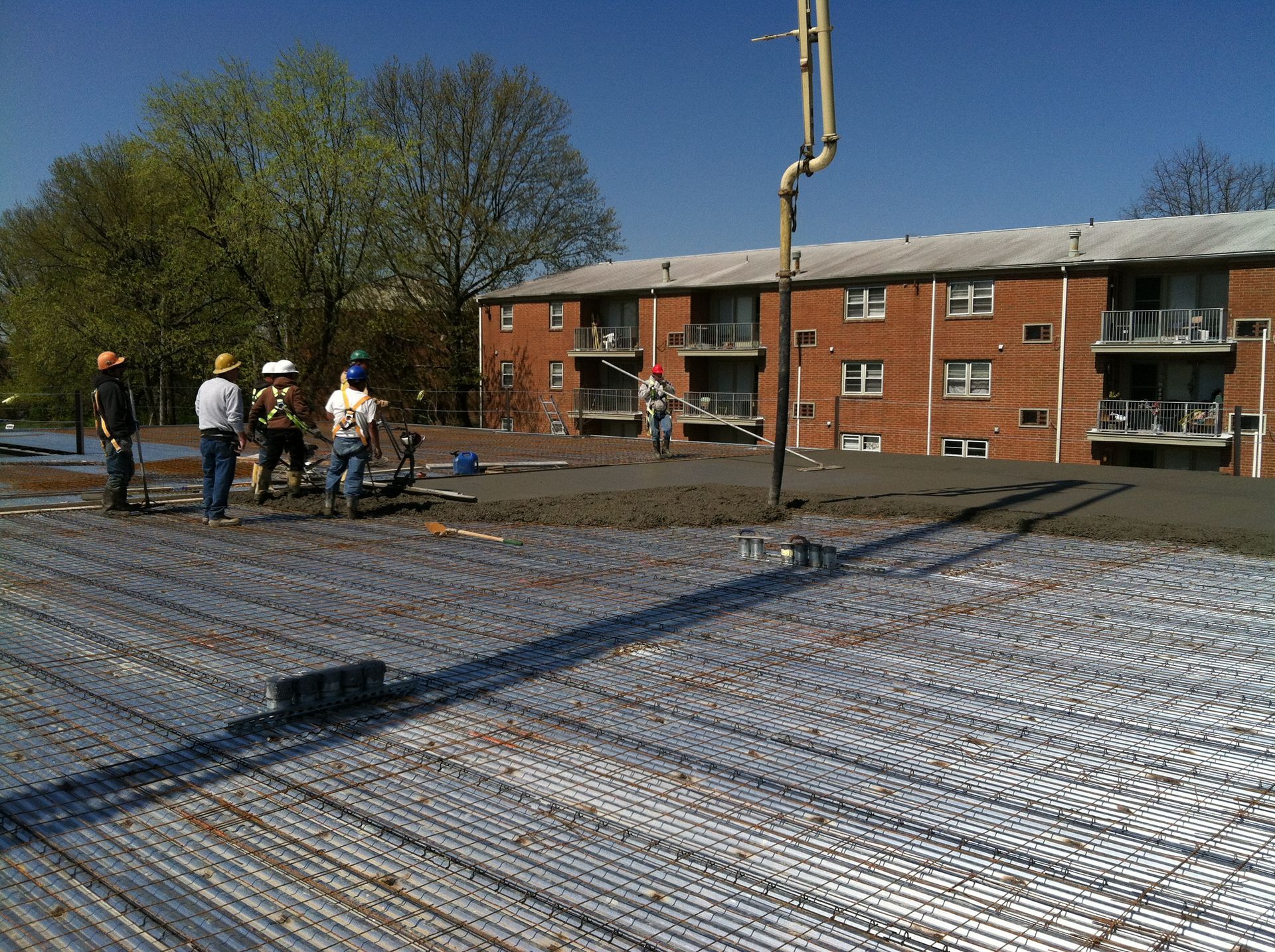 a group of construction workers are working on a concrete floor in front of a brick building