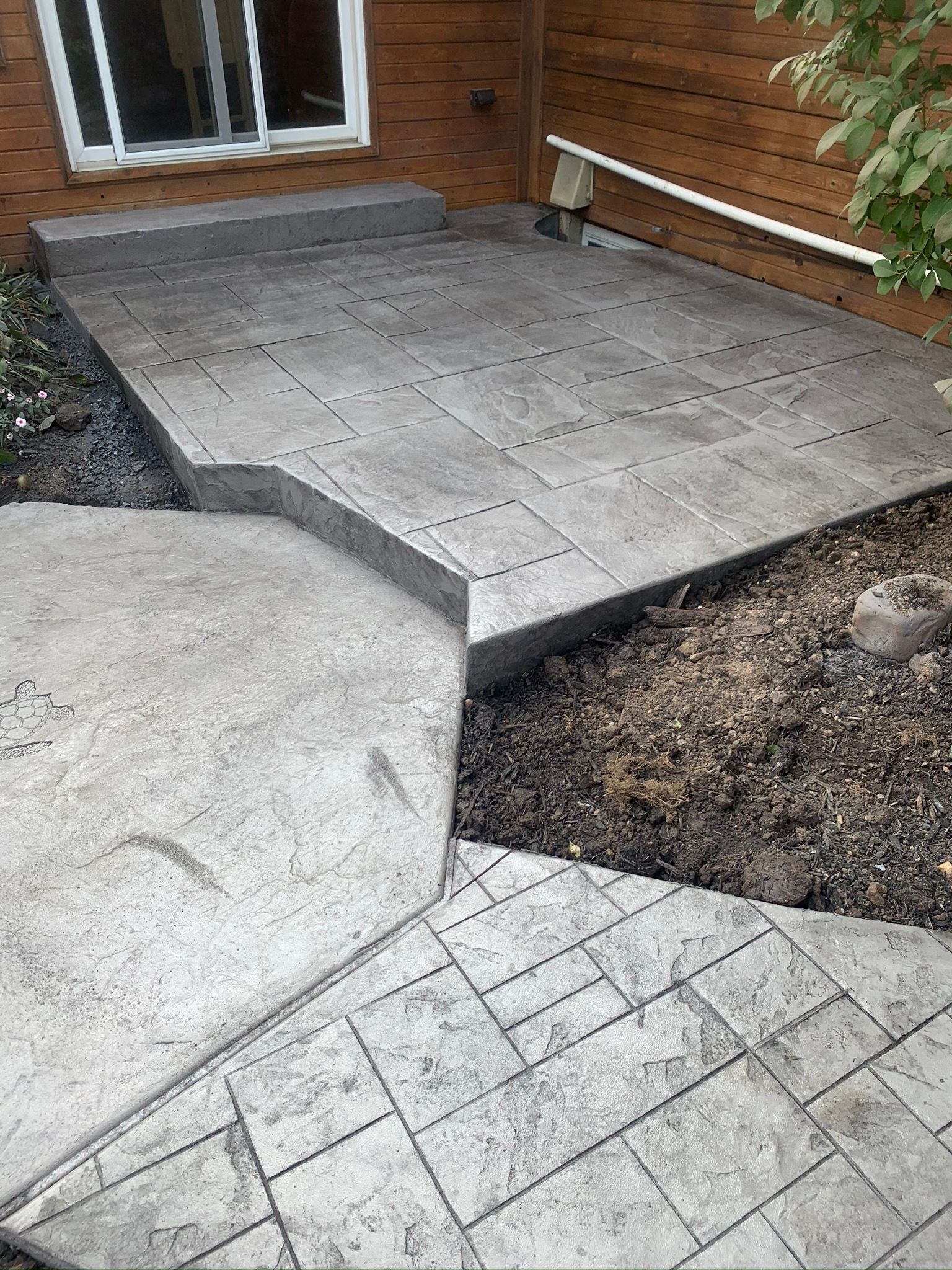 a  stamped concrete  walkway leading to a front porch of a house .