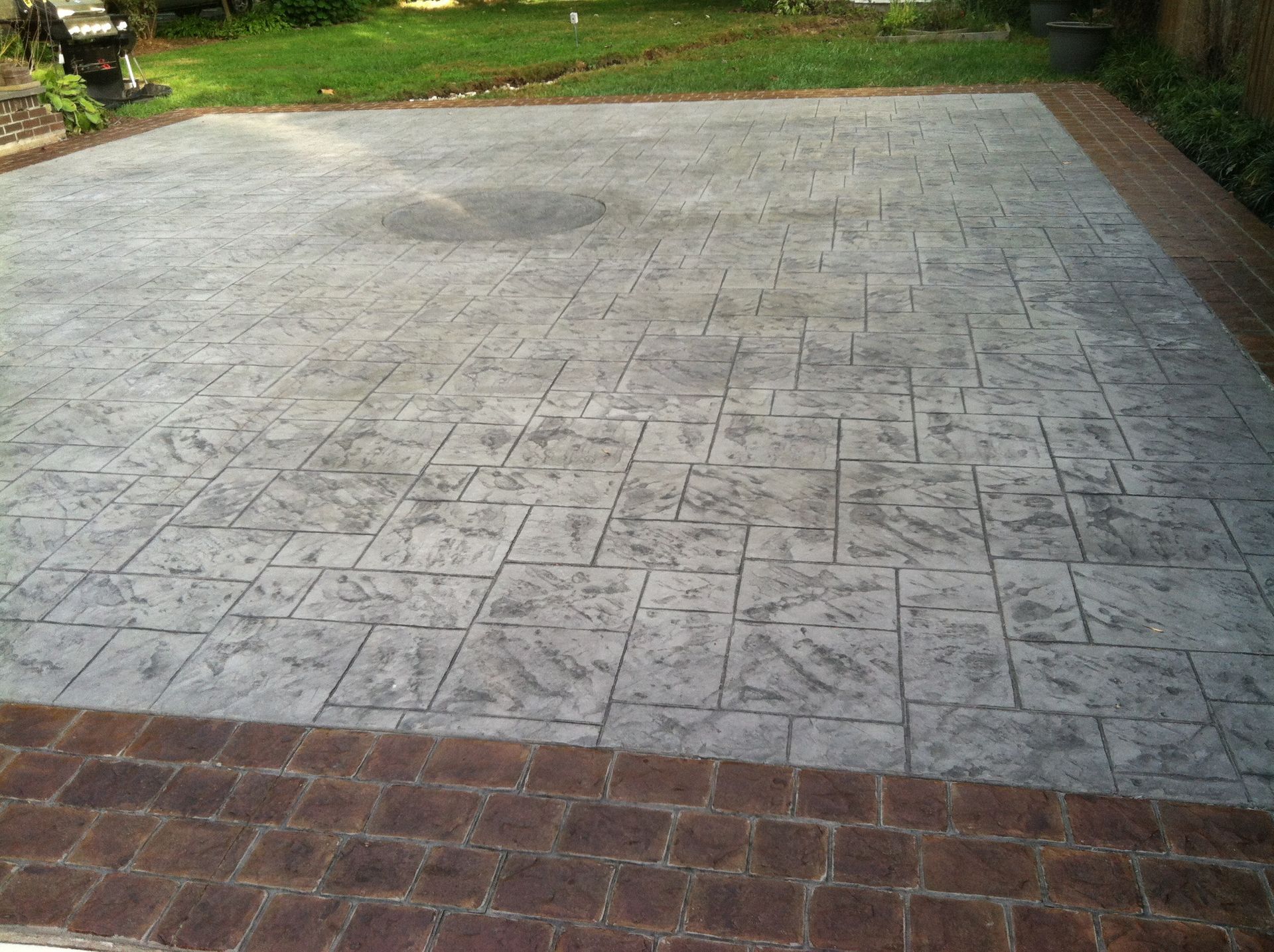 a  stamped concrete  patio with a brick border in a backyard .