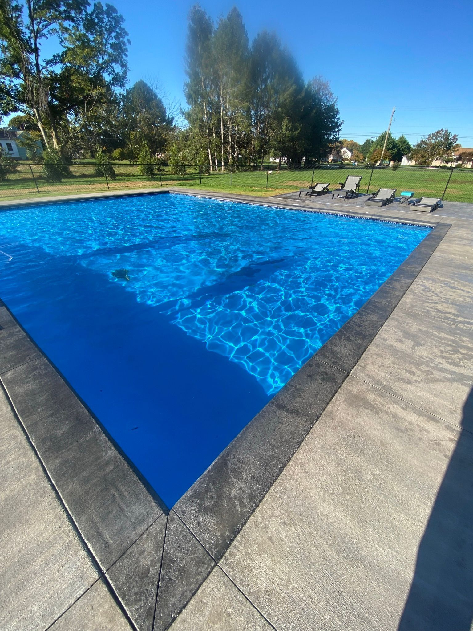 a large two toned  stamped concrete swimming pool deck.