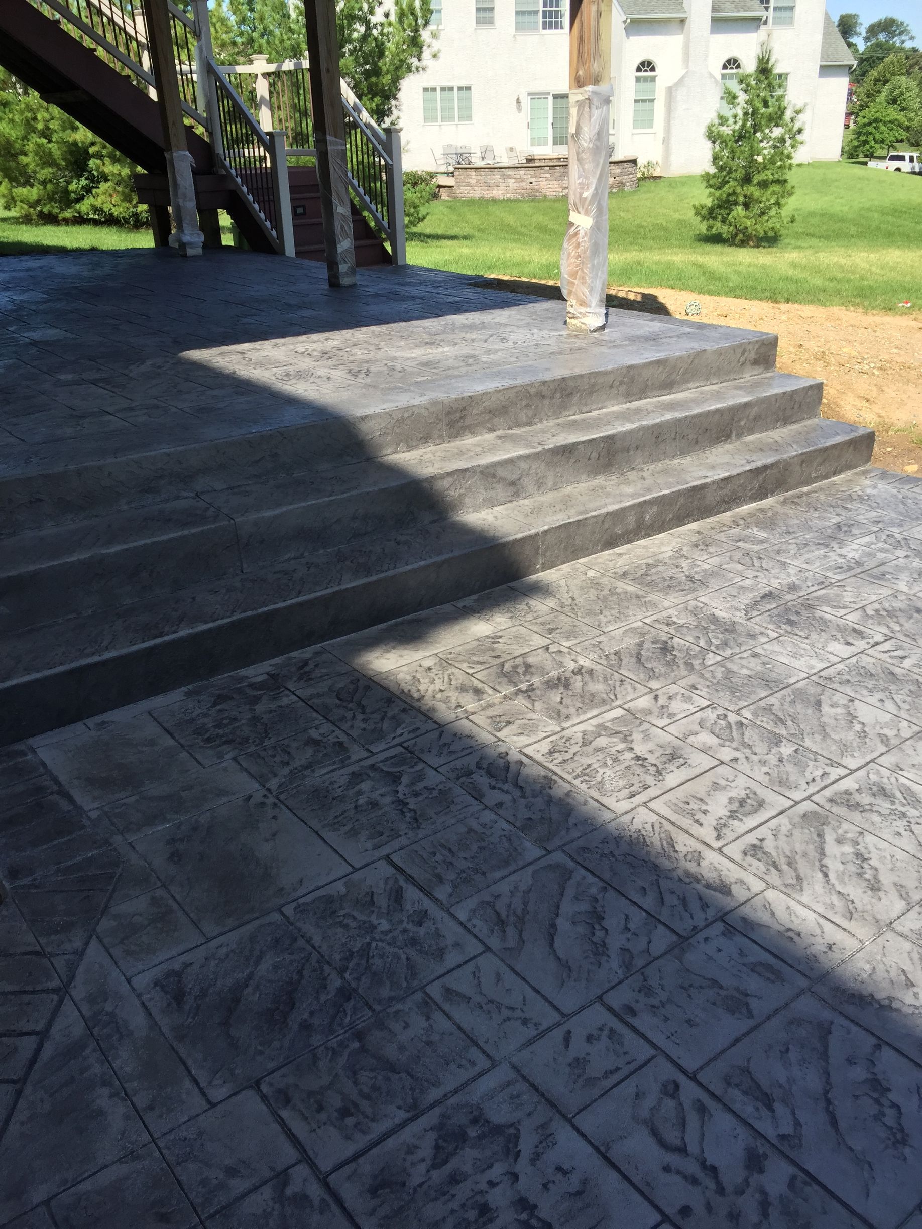 a  stamped concrete  patio with stairs leading up to it and a house in the background .