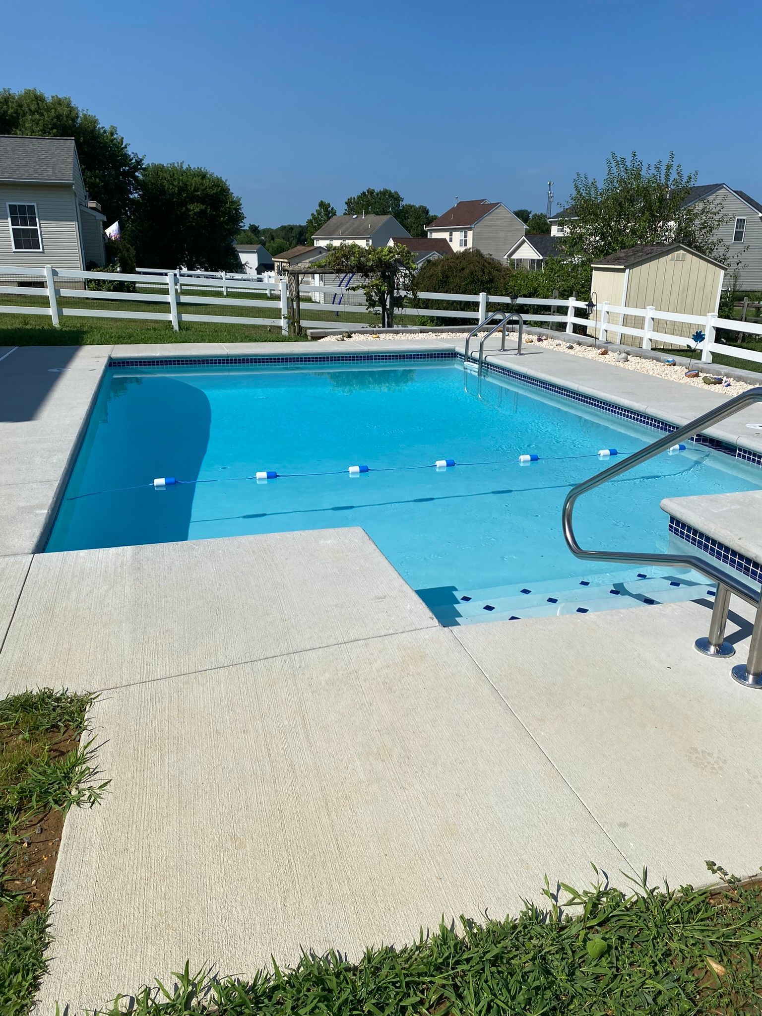 a large  stamped concrete 
 swimming pool deck with a white fence around it
