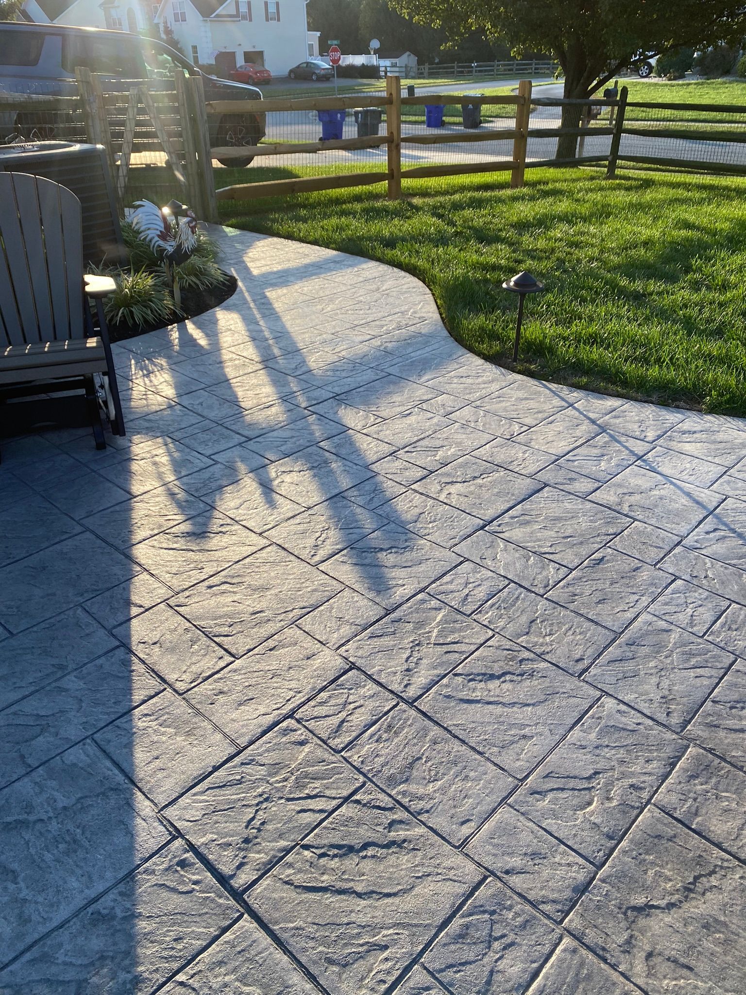 a  stamped concrete slate-like patio with a chair and a fence in the background .
