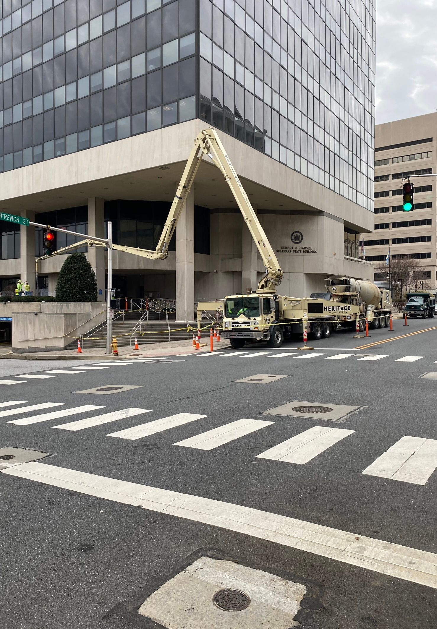 a concrete pump truck is pouring concreter for decking in front of a building .
