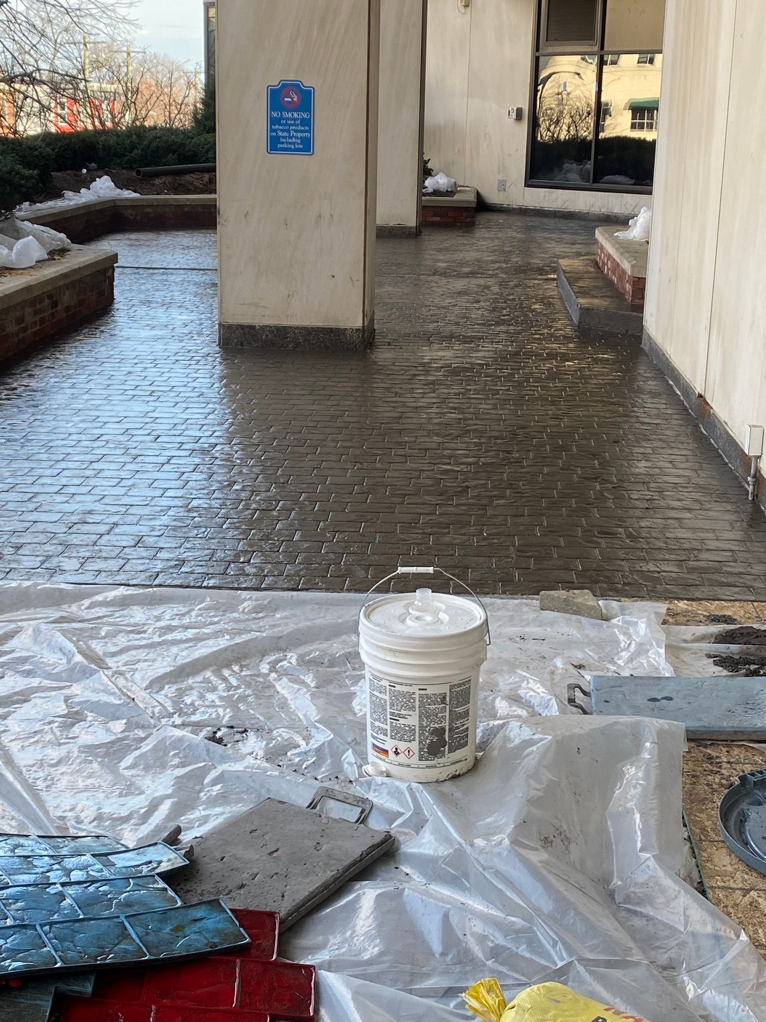 a white bucket is sitting on top of a plastic tarp on a brick floor .