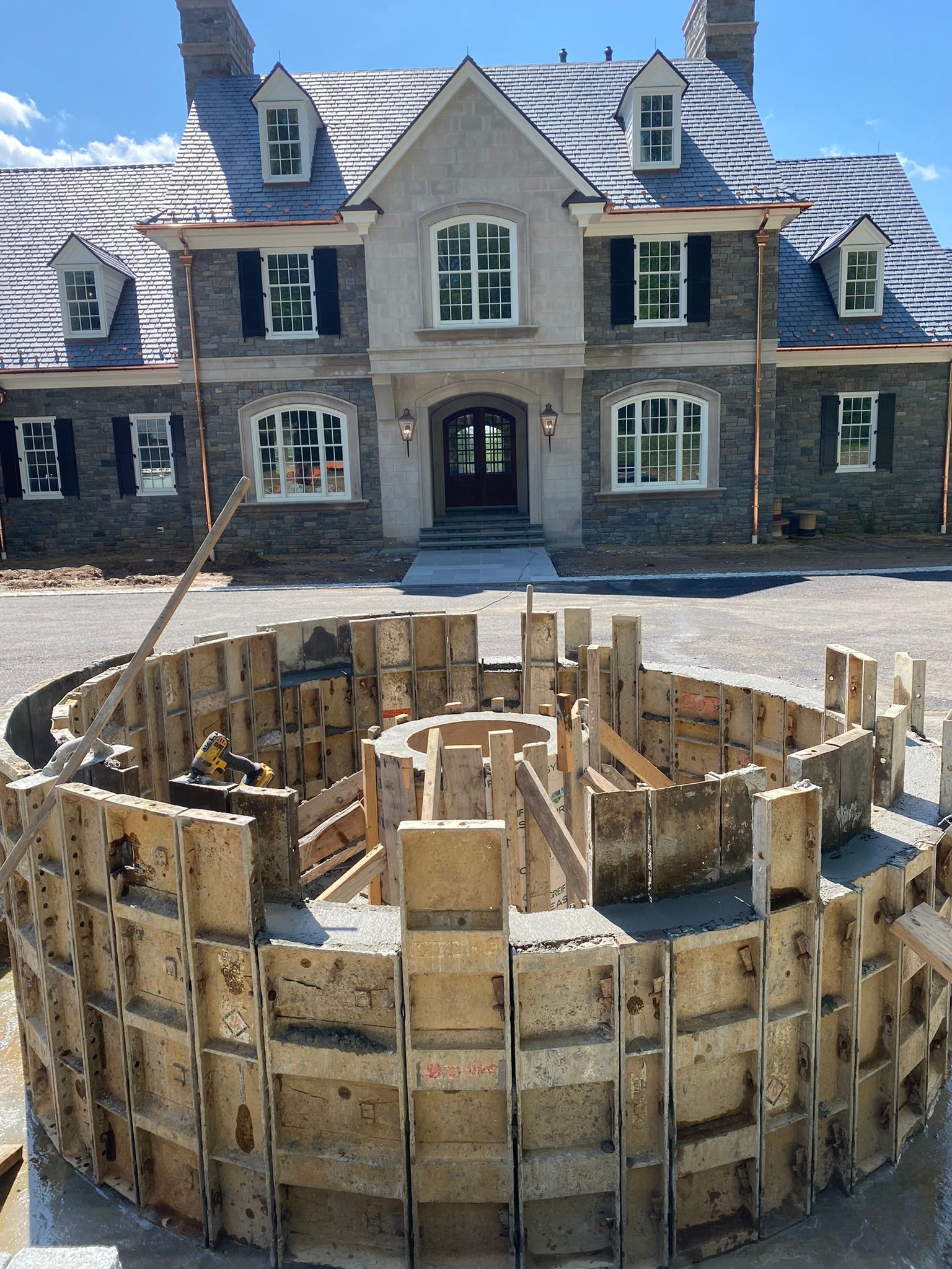 a large stone house is being built with a circular concrete structure in front of it .