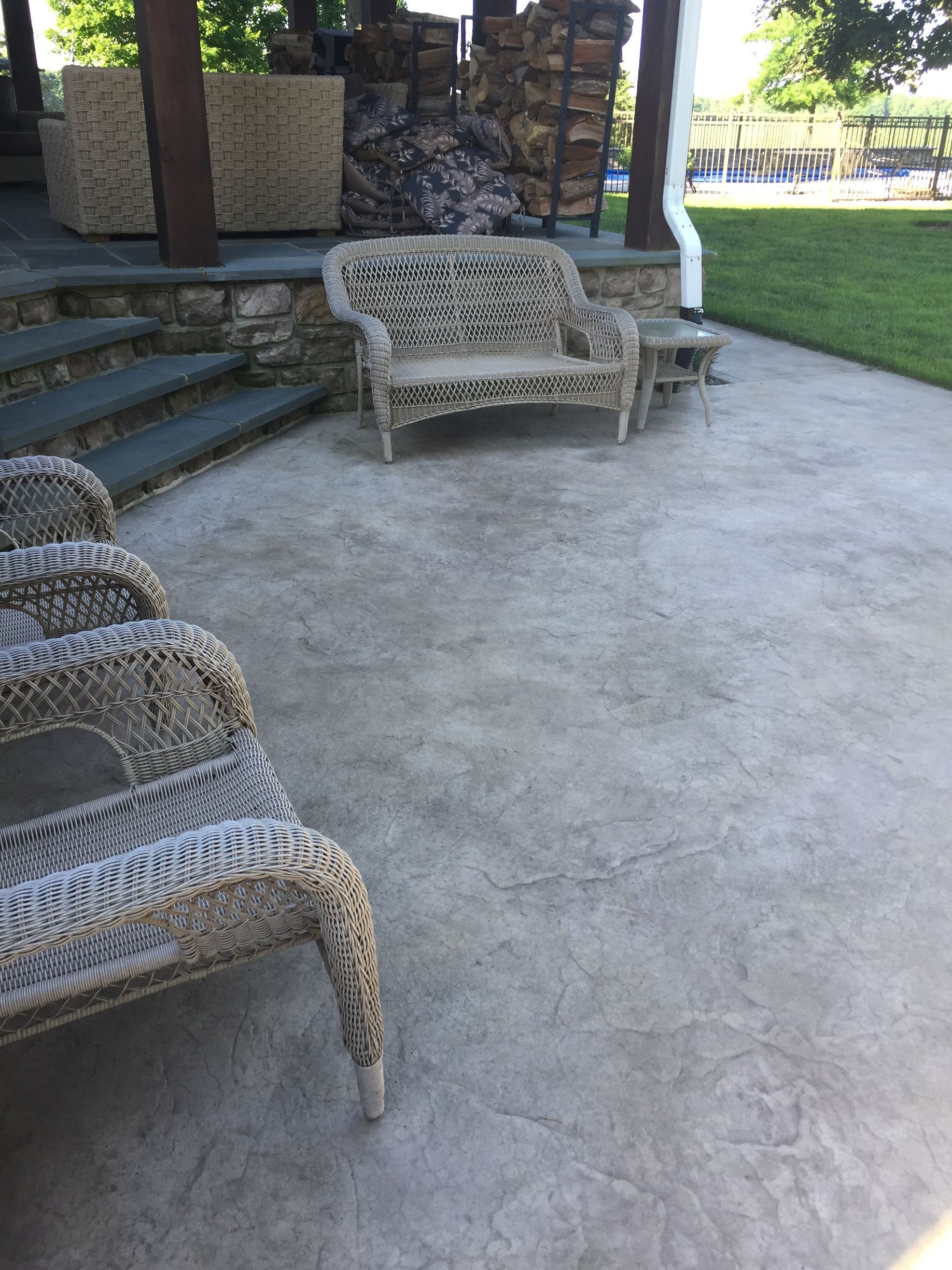 a  stamped concrete  patio with wicker furniture and a bench