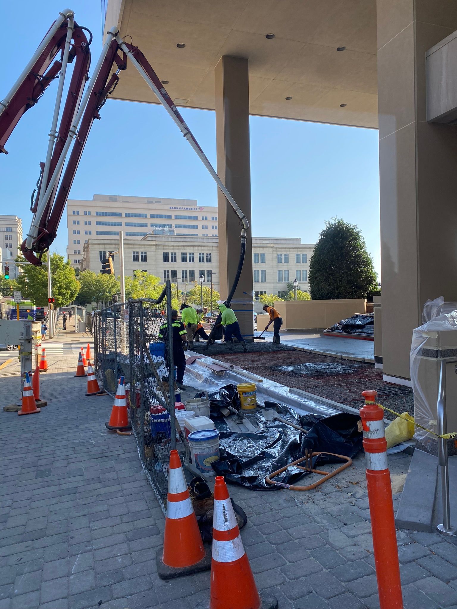 a group of construction workers are working on a sidewalk in front of a building .