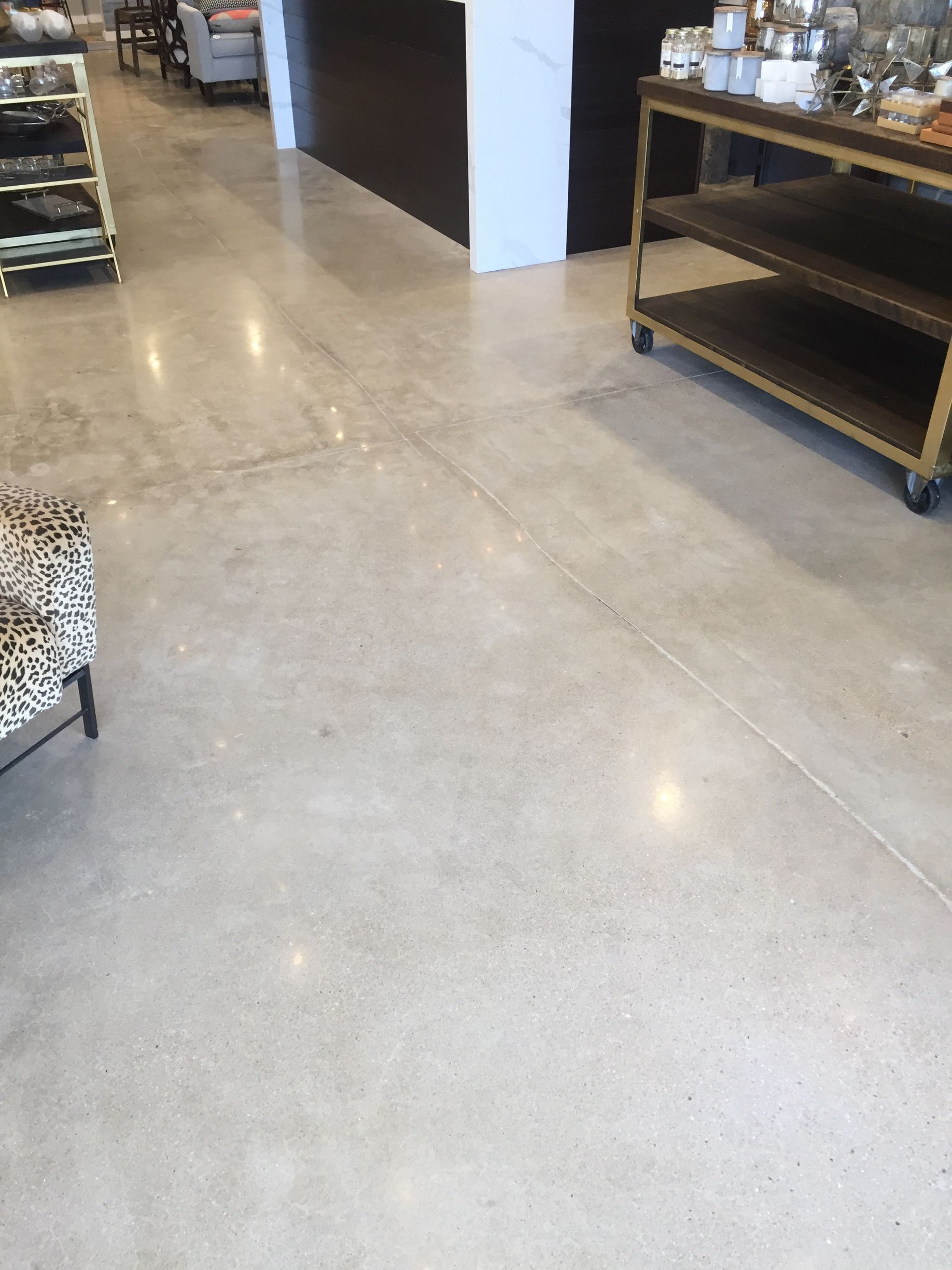 a polished concrete floor in a store with a table and chairs .