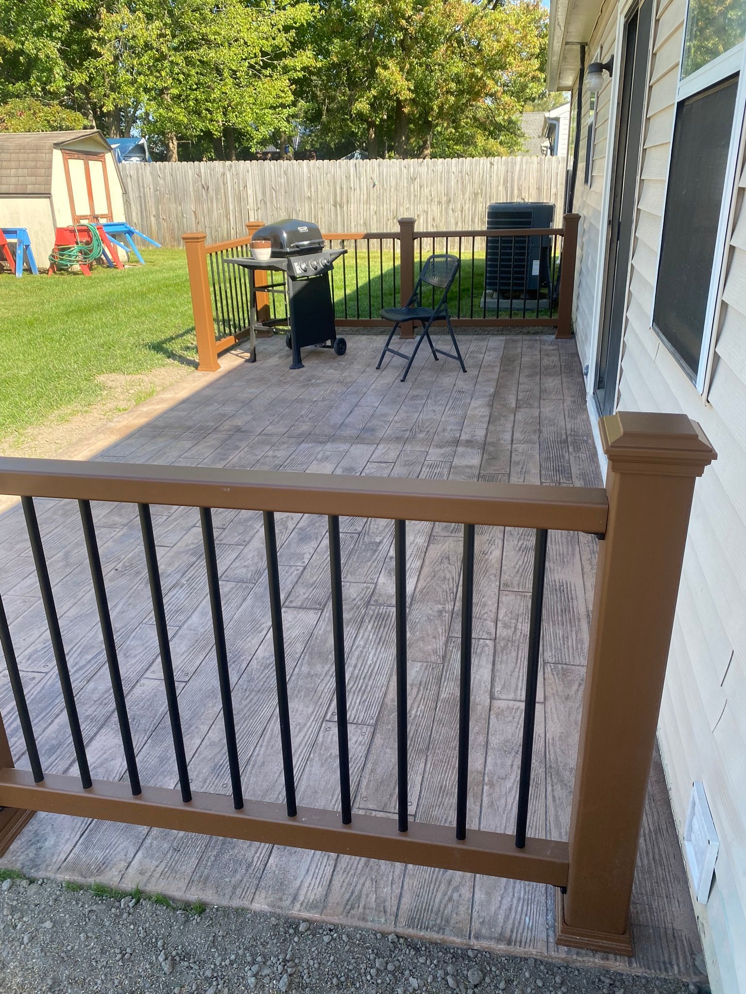 a  stamped concrete  patio with a grill and a table on it next to a house .