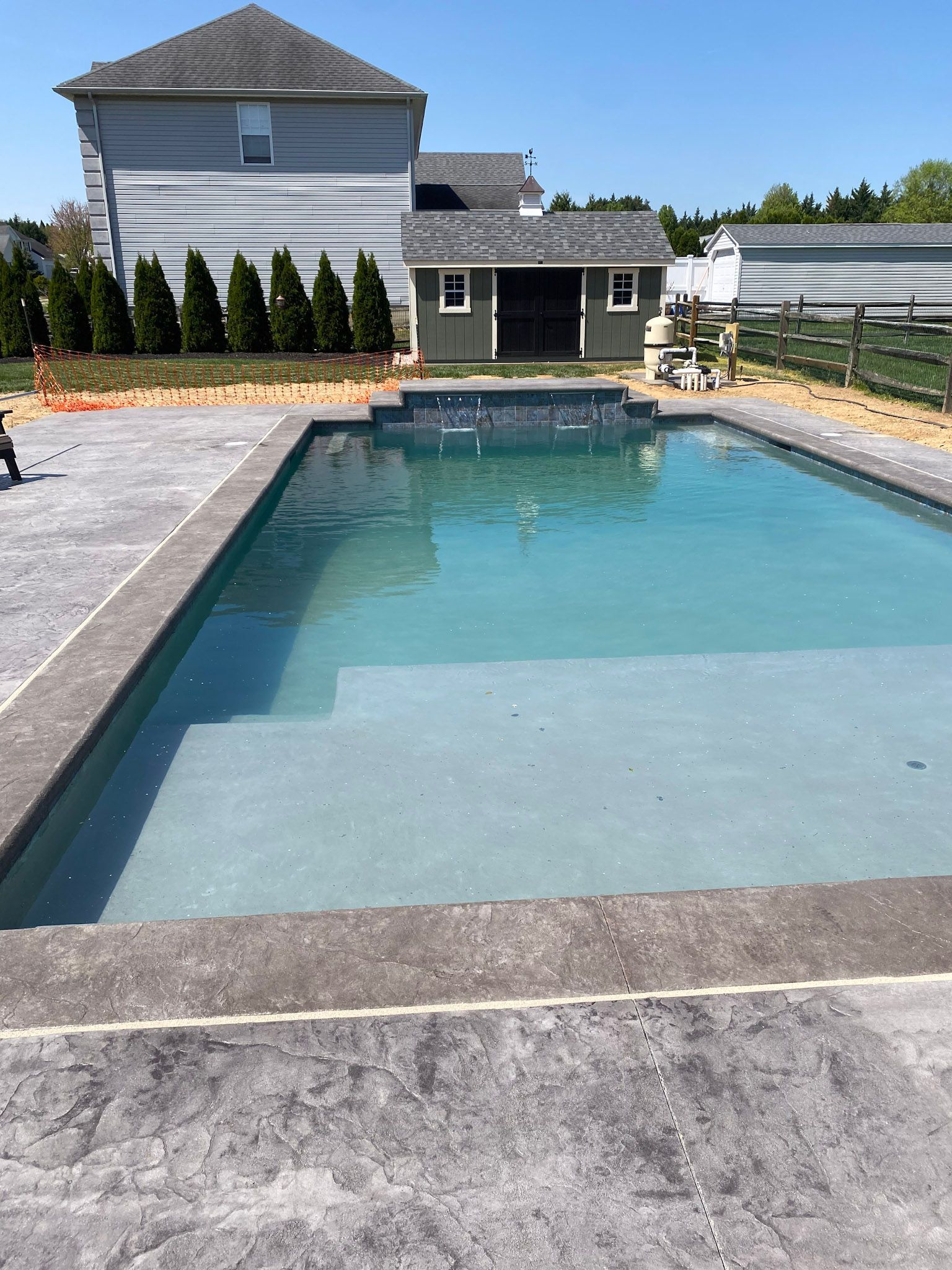 a large swimming pool with a  stamped concrete deck in the backyard of a house .