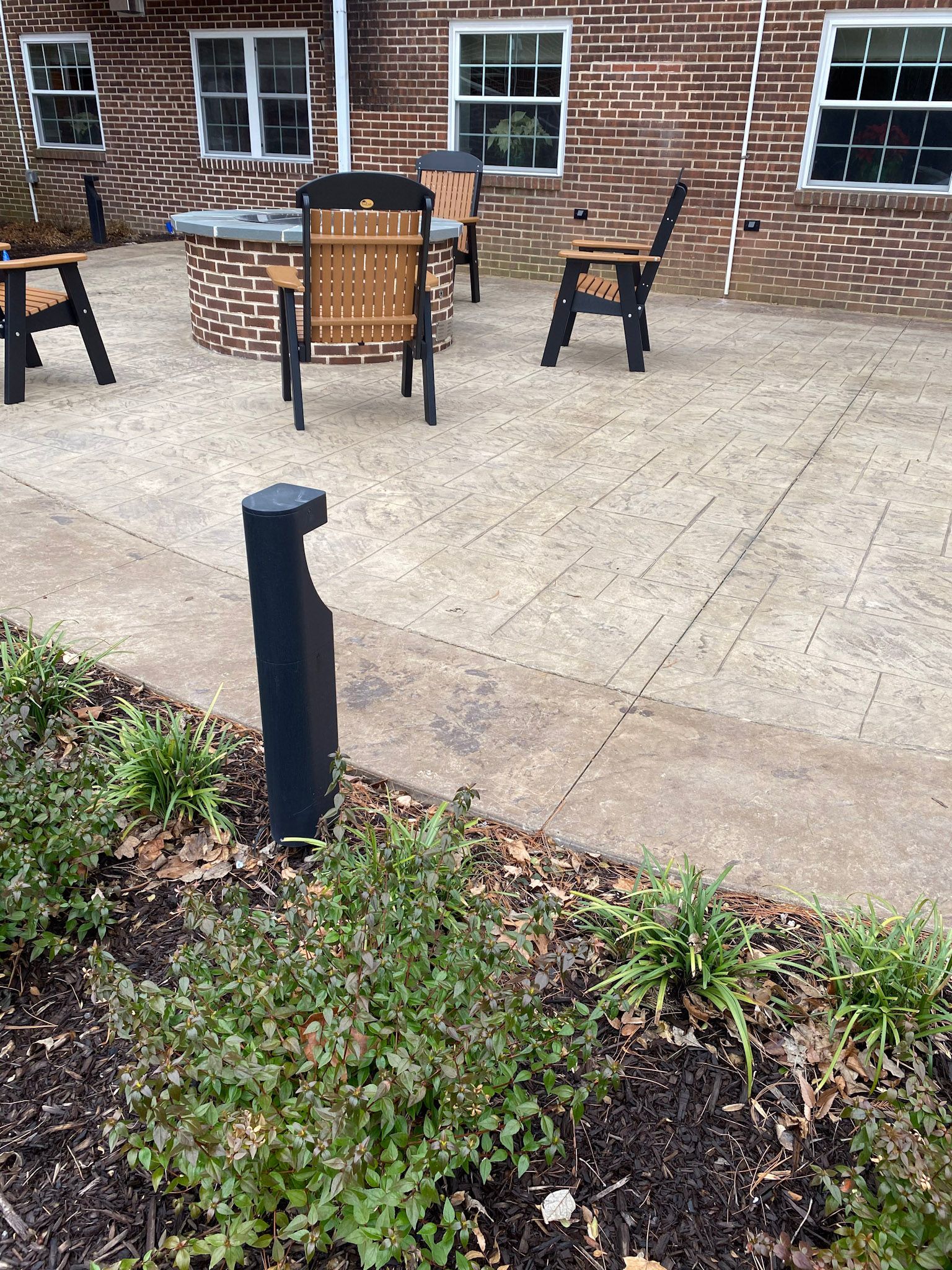 a  stamped concrete patio with tables and chairs in front of a brick building .
