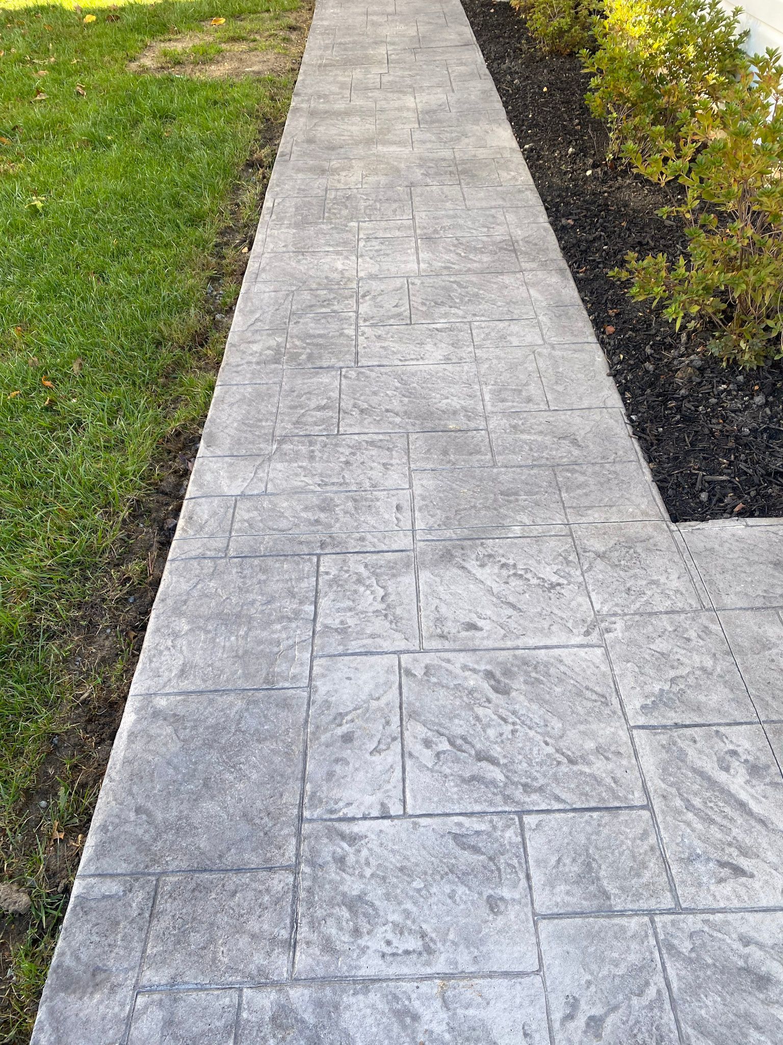a  stamped concrete 
 walkway leading to a lush green lawn .