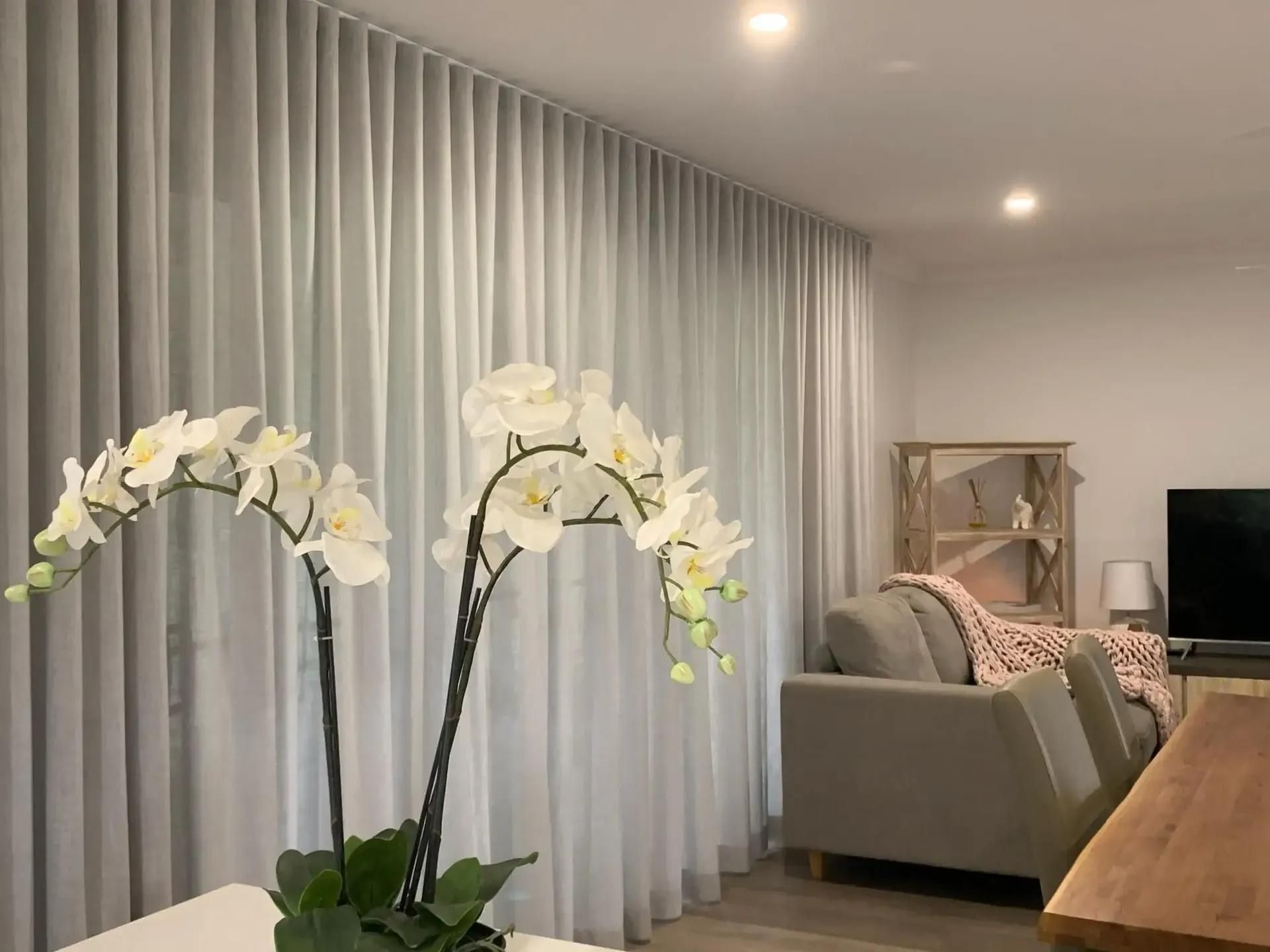 A Living Room With a Couch , Table , Television and Curtains — Mi-ekka Designs in Hamilton Island, QLD