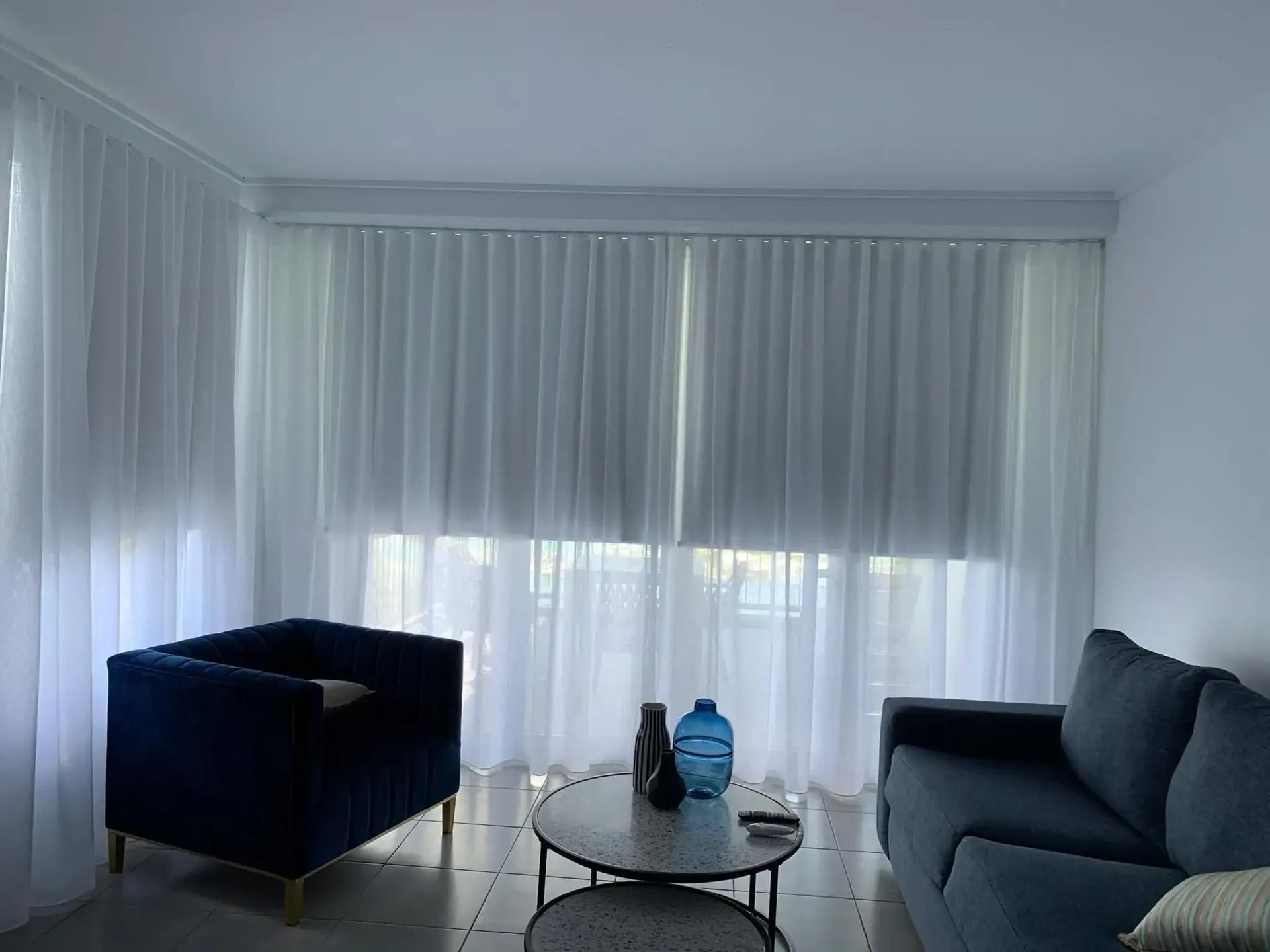 A Living Room With a Couch , Chair , Coffee Table and White Curtains — Mi-ekka Designs in Cannonvale, QLD