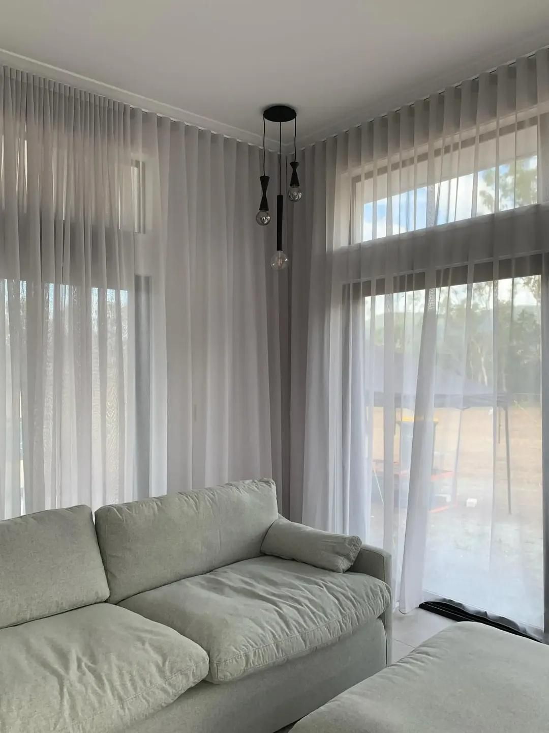A Living Room With a Couch , Ottoman , and Sheer Curtains — Mi-ekka Designs in Airlie Beach, QLD