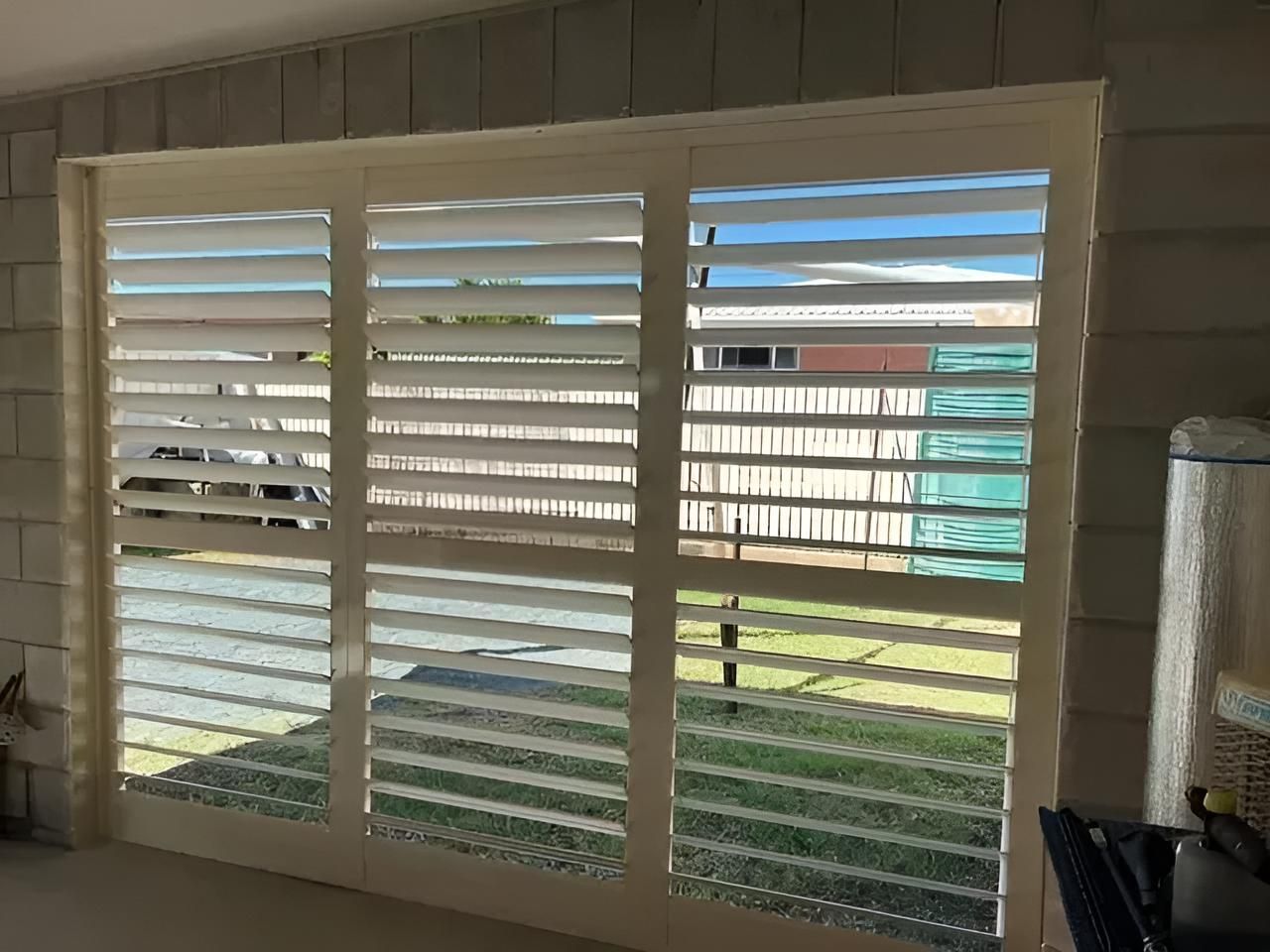 A Sliding Glass Door With White Shutters on It — Mi-ekka Designs in Cannonvale, QLD
