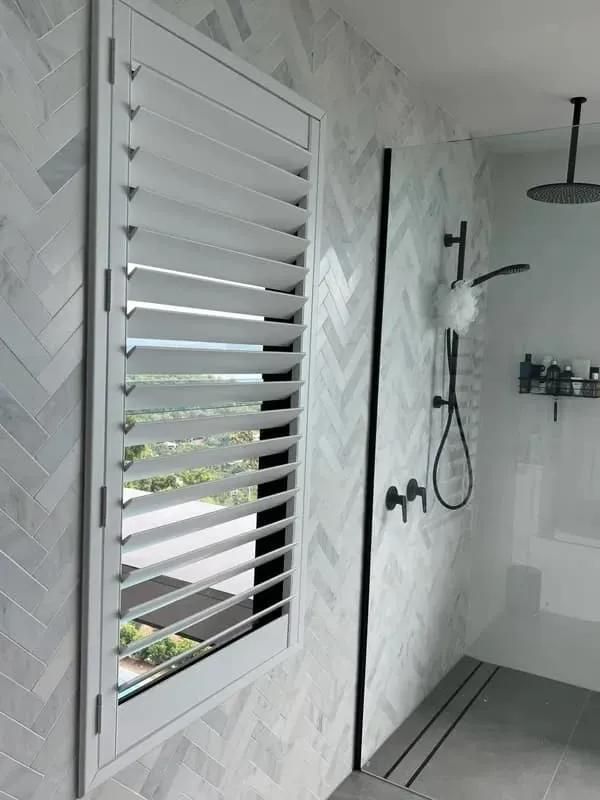 A Bathroom with A Shower and A Window with Shutters on It — Mi-ekka Designs in Cannonvale, QLD