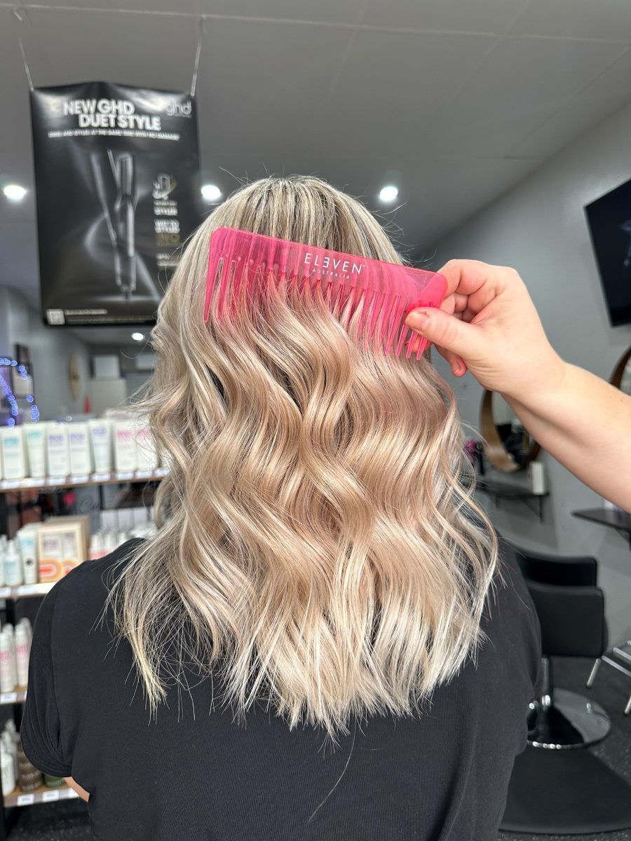 A Woman Is Getting Her Hair Combed By A Hairdresser In A Salon — Cut Loose Haircare Outlet in Evans Head, NSW