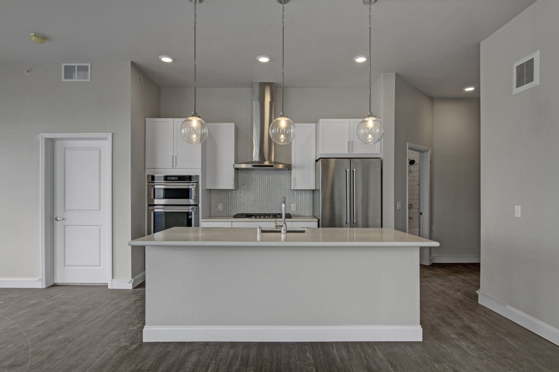 A kitchen with white cabinets, stainless steel appliances, and a large island at Daymark Uptown Apartments.