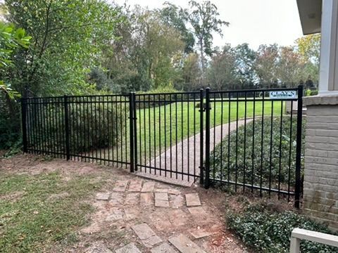 Chain-link fence with gate; a commercial area with parked trucks is in the background.
