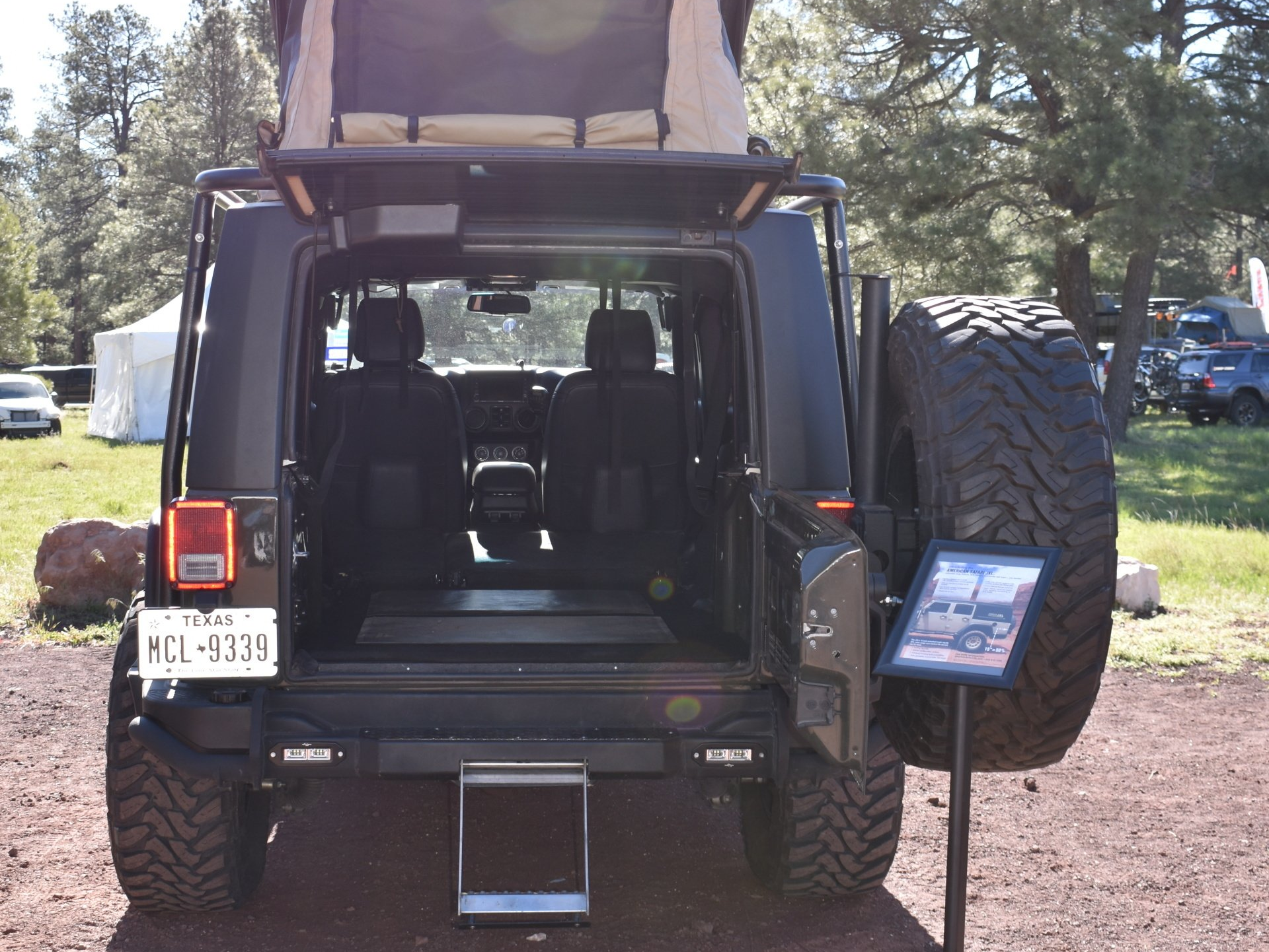 A black jeep wrangler with JXL conversion with a tent on top of it