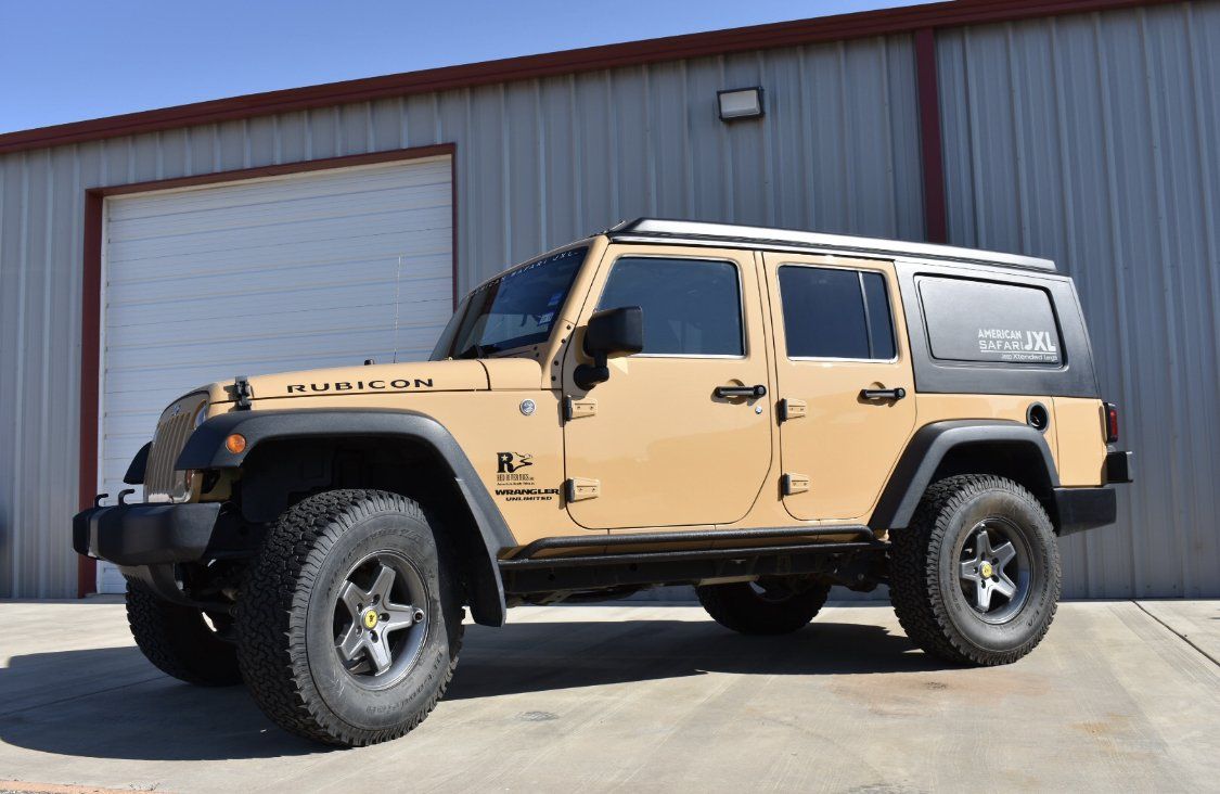 A yellow jeep JXL is parked in front of a garage door.