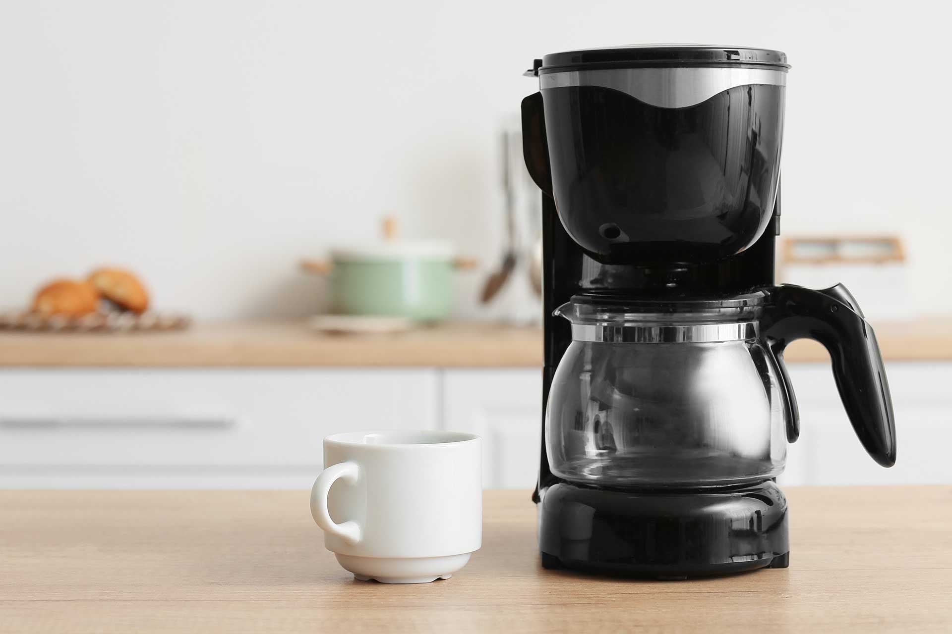 Ein Küchentisch mit einer Kaffeemaschine und einer Kaffeetasse daneben