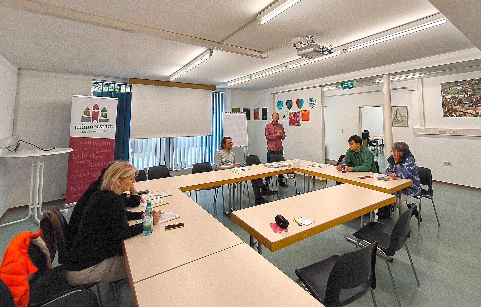 Der große Raum mit mehreren Tischen und eine Gruppe Personen bei einer Konferenz