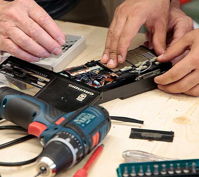 Nahaufnahme einer Person, die ein geöffnetes Elektrogerät repariert