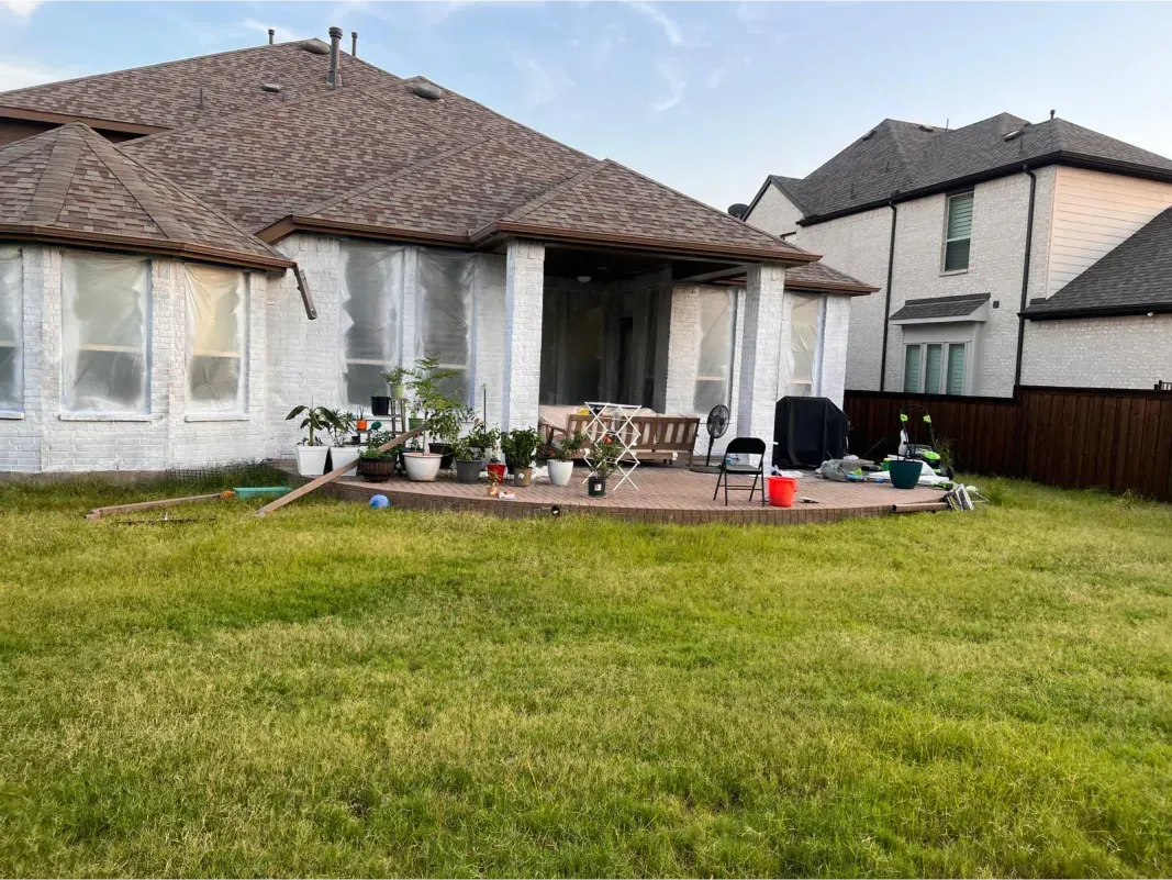 The backyard of a house with a large lawn and a deck.
