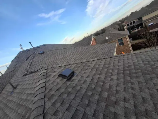A roof with a vent on it and a blue sky in the background