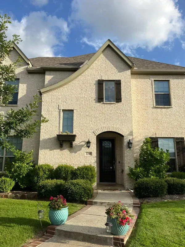 A large white brick house with a black door and shutters