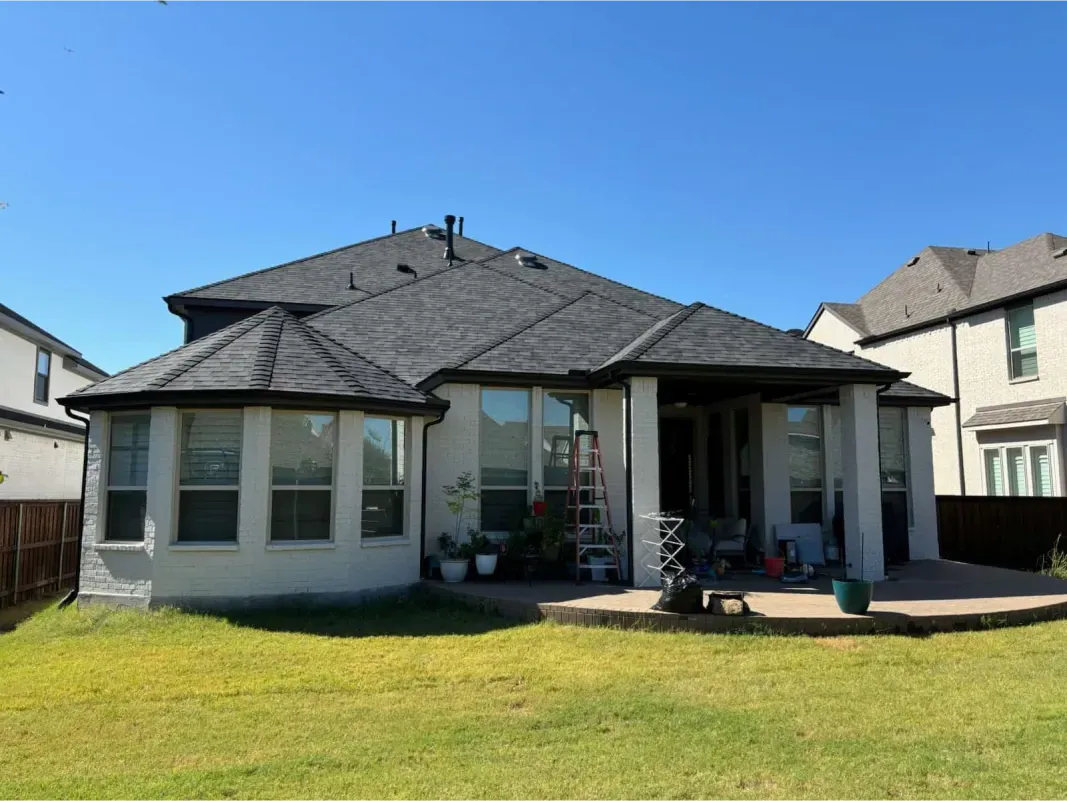 The back of a house with a large lawn in front of it.